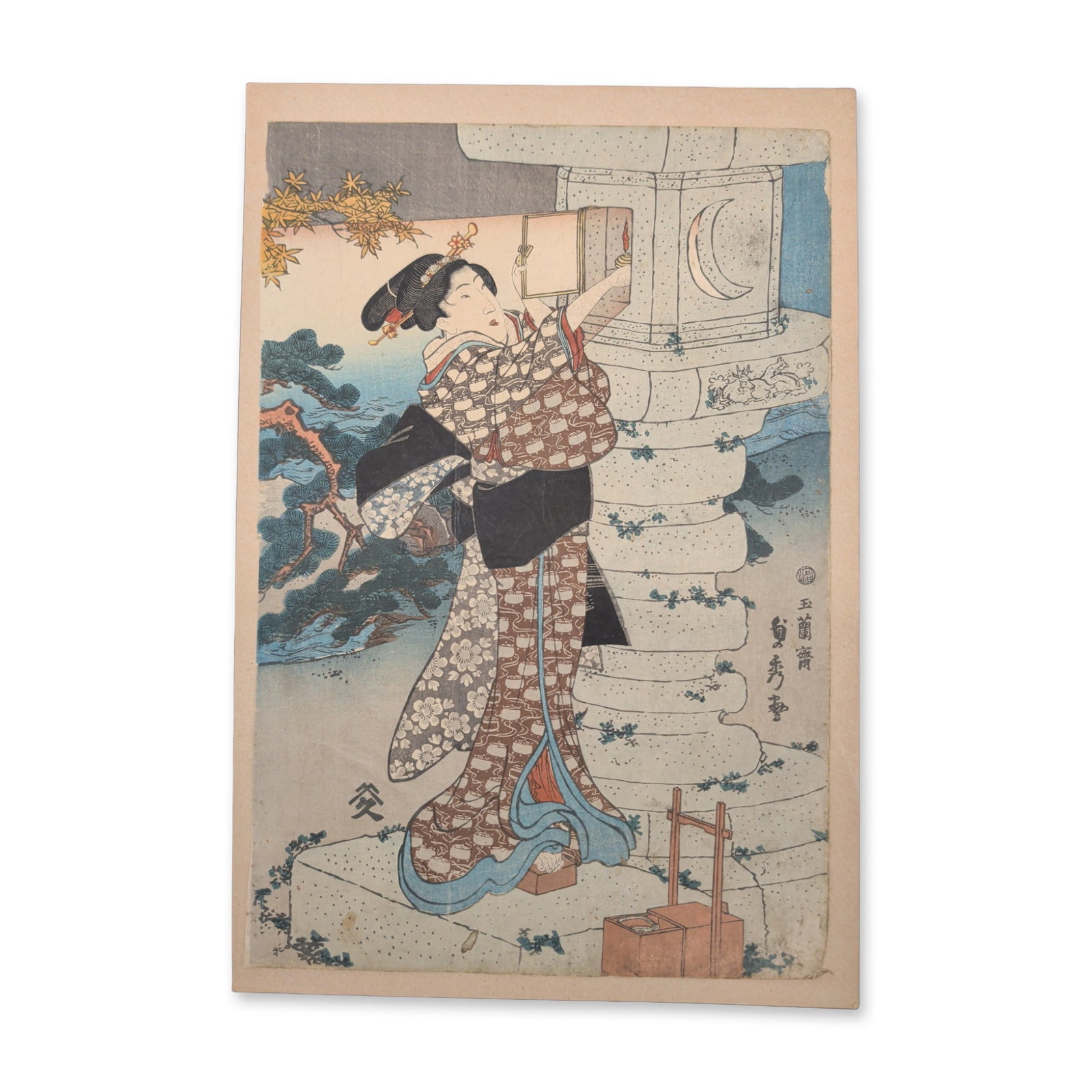 Utagawa Kunisada (Toyokuni III) (Japanese, 1786-1865) Woodcut on Paper Woman by a Crescent Moon: This 19th-century Japanese woodcut features a vertical nighttime scene portrays an elegantly styled woman in heavily patterned floral robes standing balanced atop a stone block. She reaches upward tow