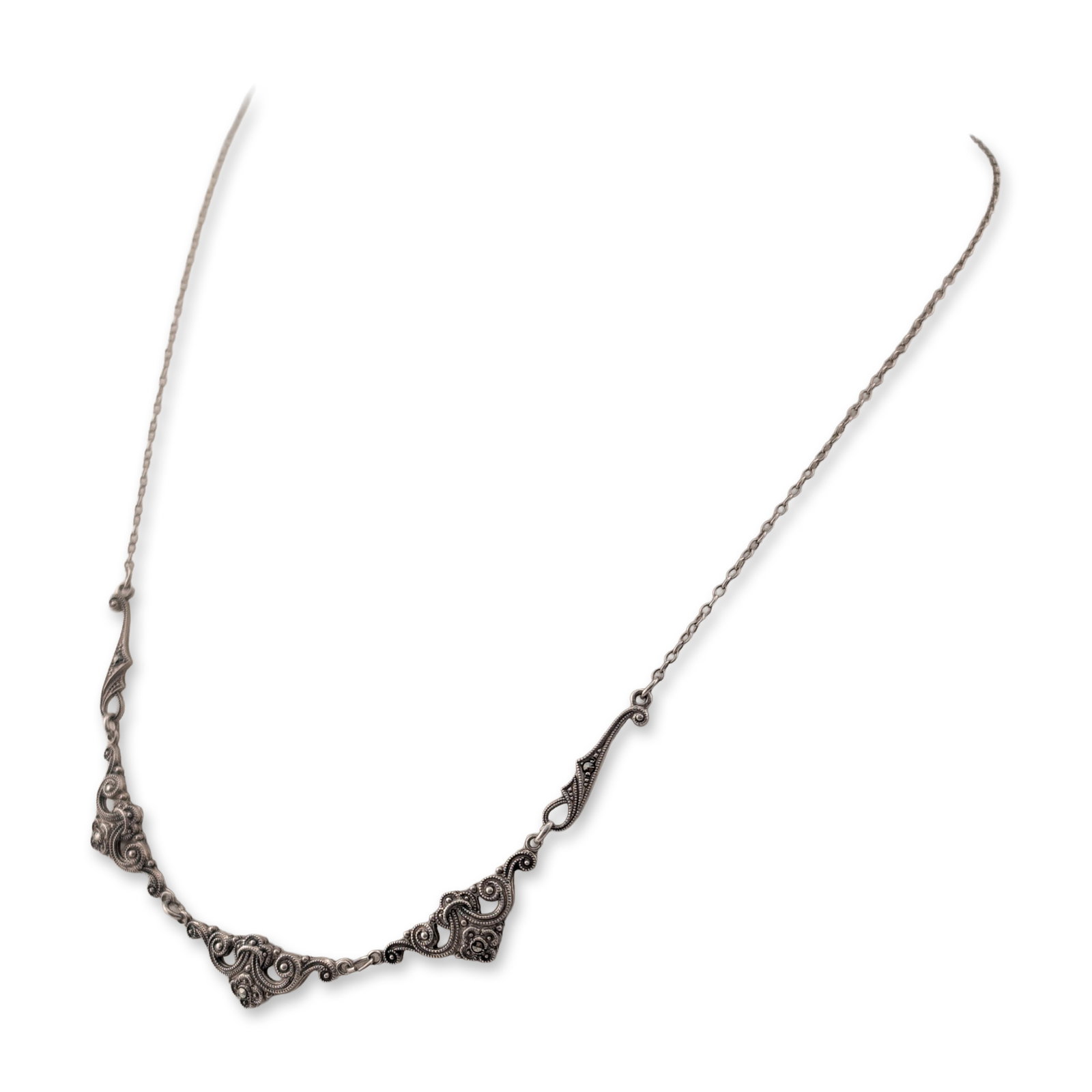 Sterling Silver and Marcasite Scrolling Filigree Style Necklace: Sterling silver and marcasite necklace in a scrolling filigree-inspired design. The central station consists of five linked openwork elements featuring foliate scrolls set with numerous round