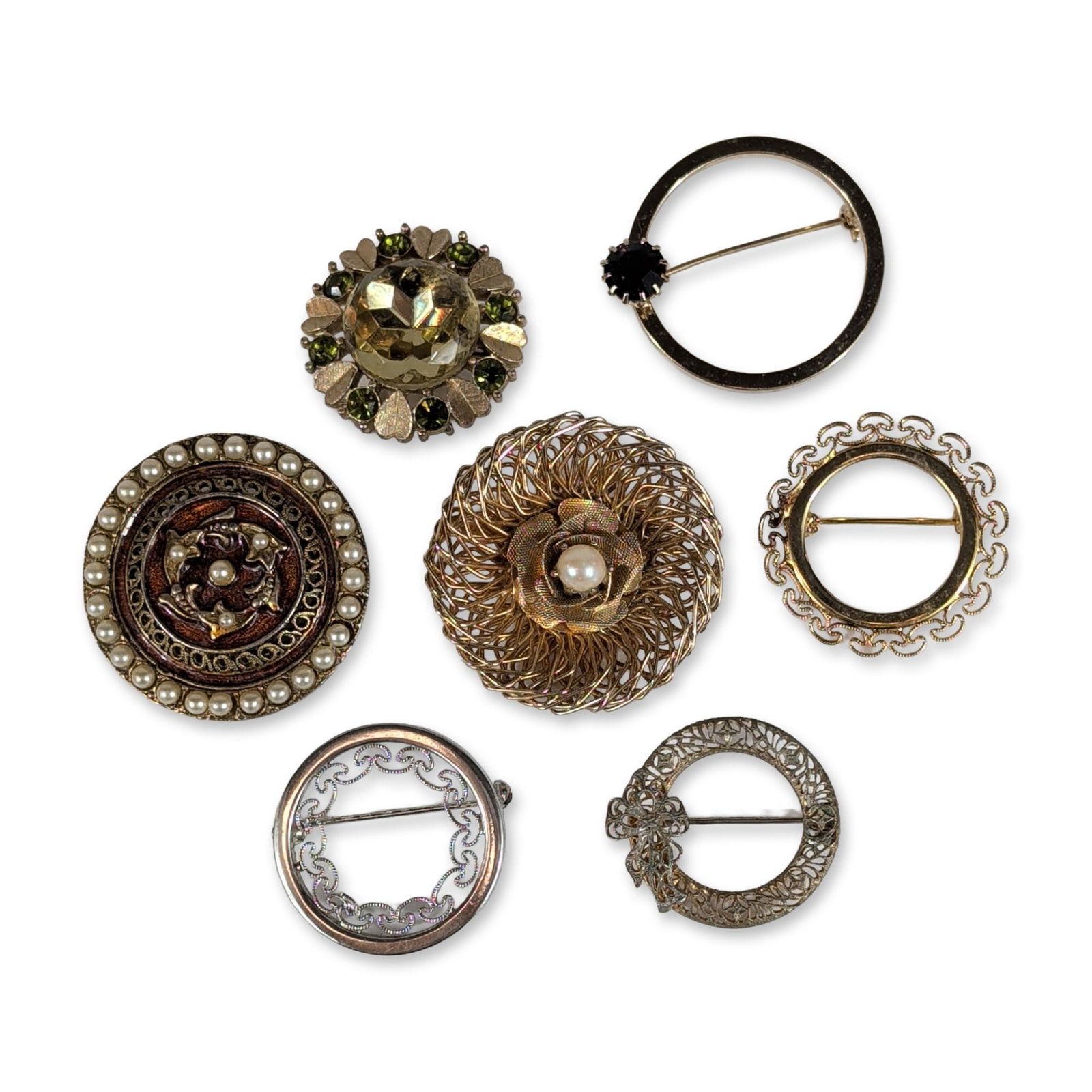 Collection of Seven Vintage Costume Brooches: A collection of seven vintage costume jewelry brooches in assorted gold-tone and silver-tone base metals. The group features mid-20th-century designs including a large gold-tone wirework nest brooch c