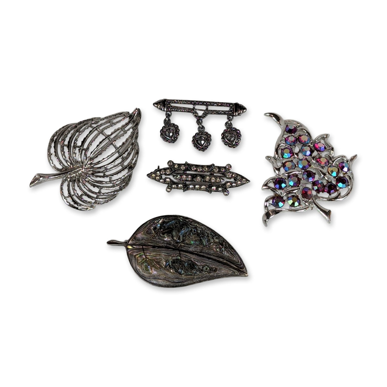 5pc Vintage Silver Tone and Sterling Brooches: Assortment of vintage brooches in silver tone and sterling silver, featuring botanical and geometric motifs. Includes a Sarah Coventry silver tone leaf brooch set with faceted purple and blue aurora b