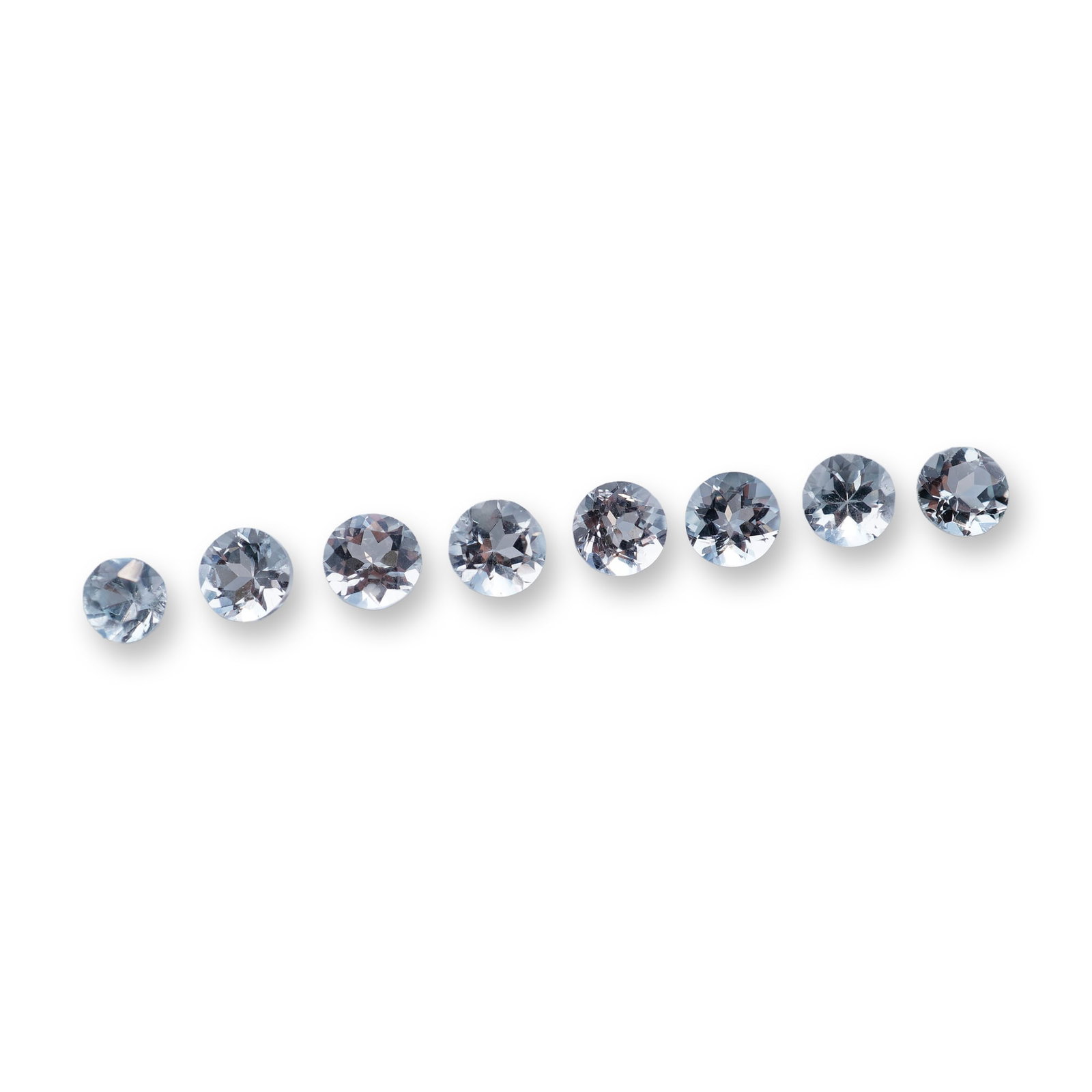 Group of Round Brilliant Cut Aquamarine Gemstones: A group of loose aquamarine gemstones featuring round brilliant cuts. The stones exhibit a uniform pale, icy blue hue with high transparency and an eye-clean appearance. Faceting is well-defined with 