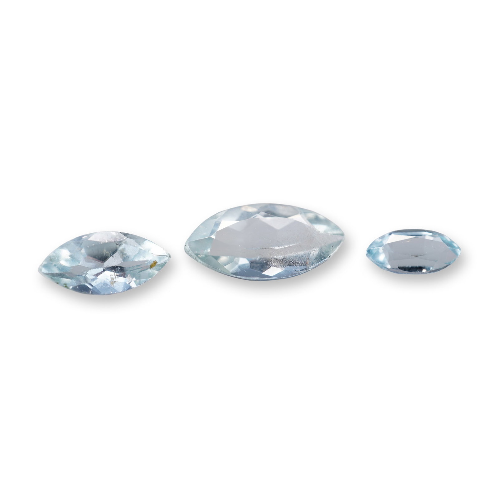 Trio of Marquise Cut Blue Aquamarine Gemstones: Trio of faceted marquise-cut loose aquamarine gemstones in a pale blue color, featuring pointed ends and elliptical shapes in graduated sizes. Stones demonstrate high transparency with uniform light