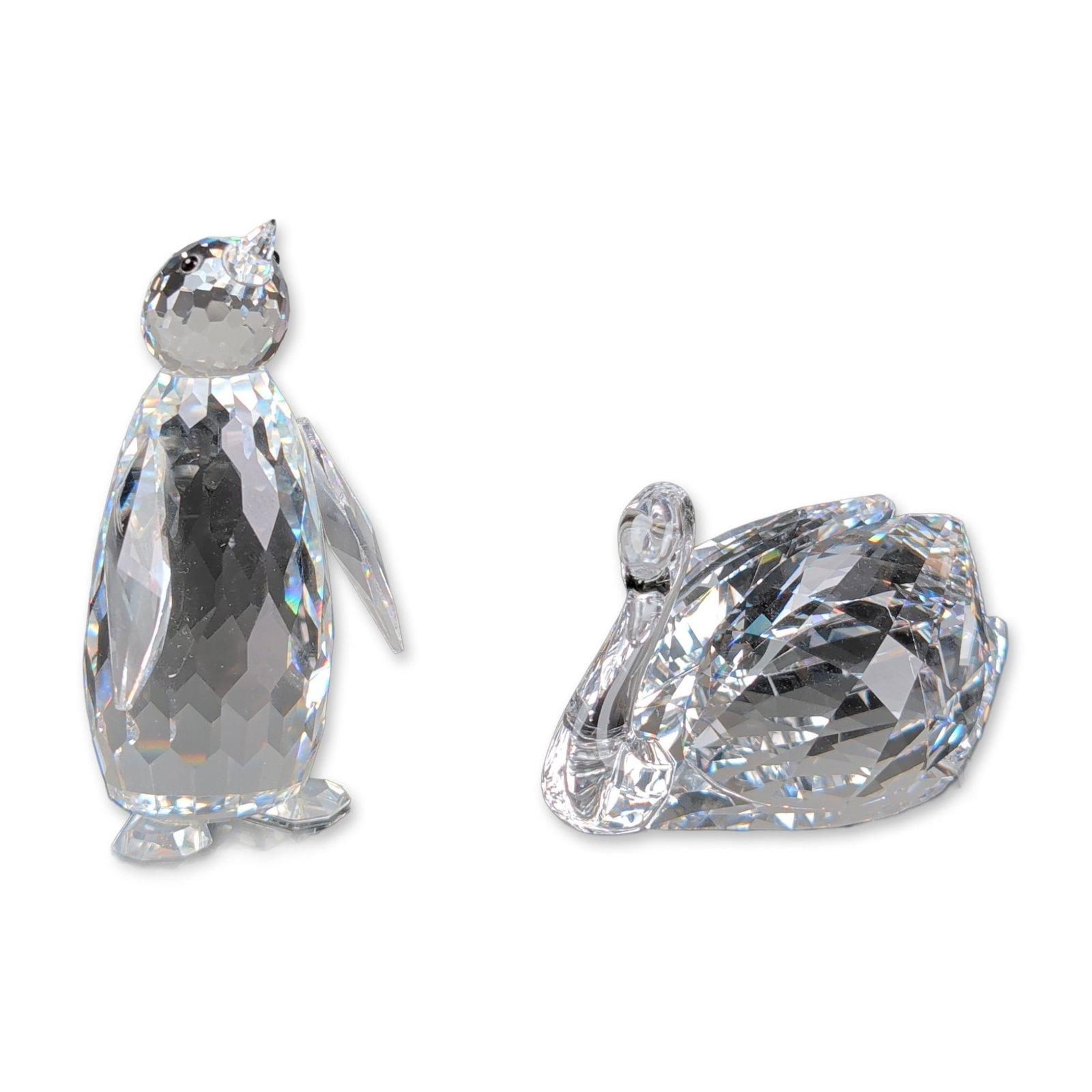 Two Swarovski Silver Crystal Animal Figurines, Swan and Penguin: Two faceted lead crystal animal figurines comprising a swan with dark bead eyes and a standing penguin. Swarovski acid mark on bases. Lot includes original manufacturer packaging consisting of one blu
