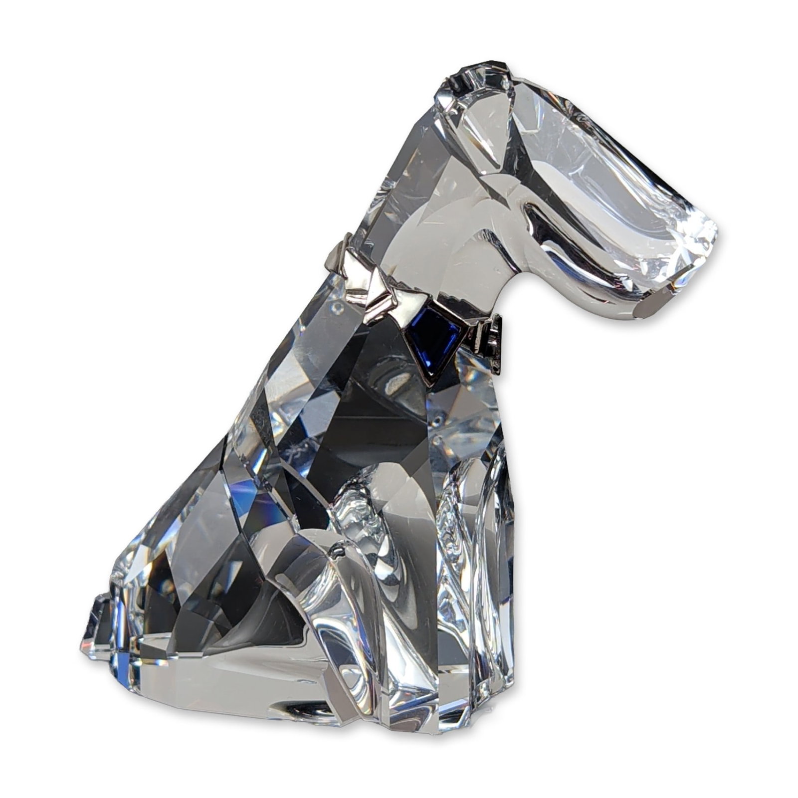 Swarovski Austrian Crystal Symbols Dog Figurine: Swarovski Dog figurine in faceted clear crystal, featuring a metallic silver-toned collar inset with a single triangular dark blue faceted crystal. Etched swan maker mark and copyright symbol located 