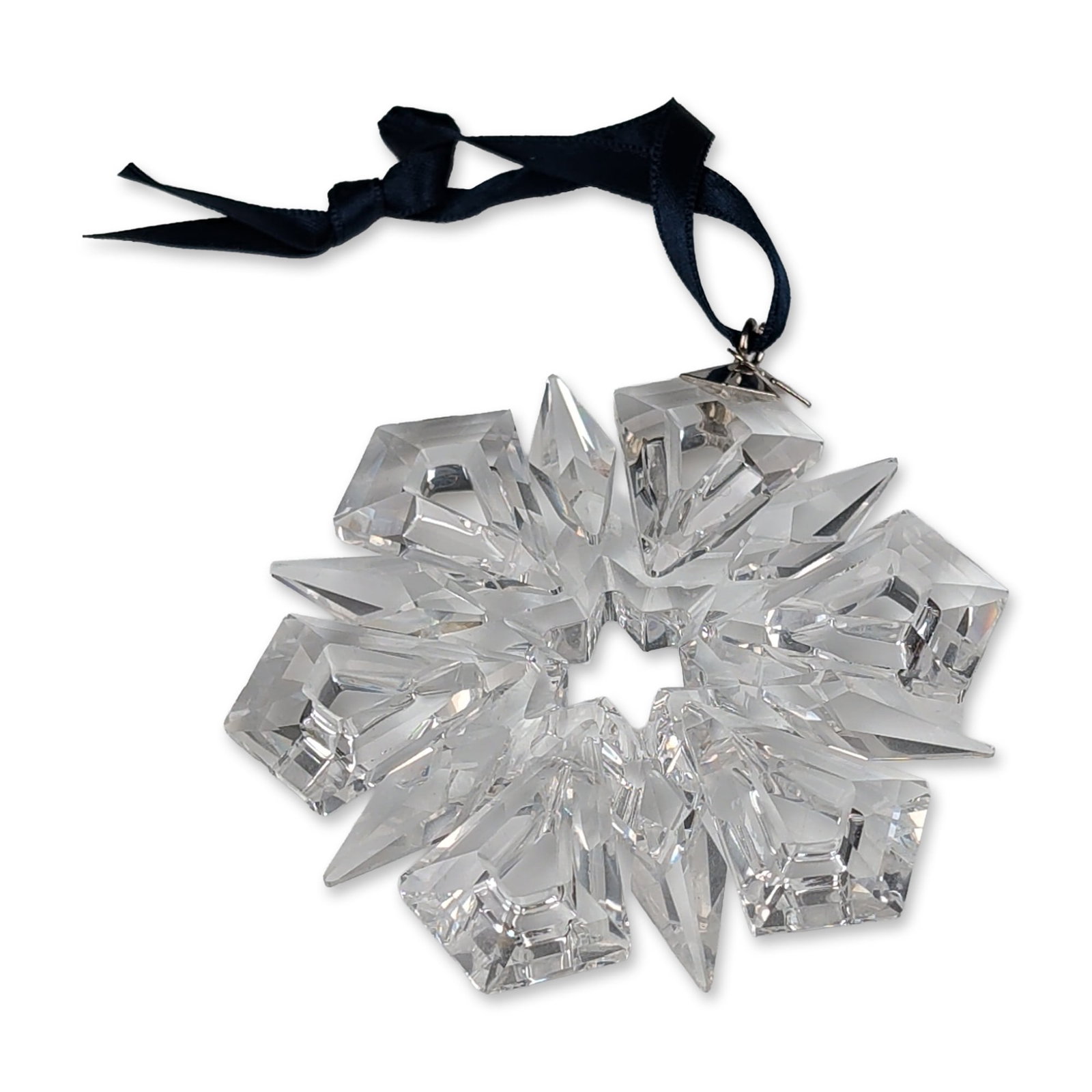 Swarovski 1999 Annual Edition Crystal Snowflake Ornament: Swarovski 1999 annual edition Christmas snowflake ornament in faceted clear crystal, featuring a six-pointed star design with central hexagonal aperture and dark blue satin ribbon. Silver-tone metal t