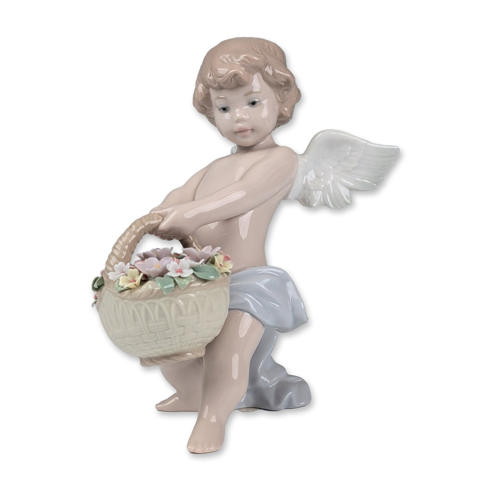Lladro Glazed Porcelain Figurine, Heaven's Harvest 01008676: Lladro (Spain). Glazed porcelain figurine depicting a winged cherub carrying a large woven-texture basket filled with hand-modeled flowers in shades of pink, yellow, and white. The figure is modeled w