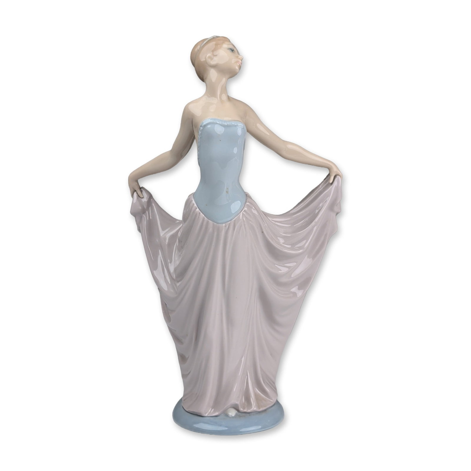 Lladro Porcelain Figurine, Dancer 01005050: Porcelain figurine sculpted by Vincente Martinez. The figure depicts a young woman in a dance pose with arms extended holding a lavender-grey skirt with deep vertical folds. She is wearing a pale blue
