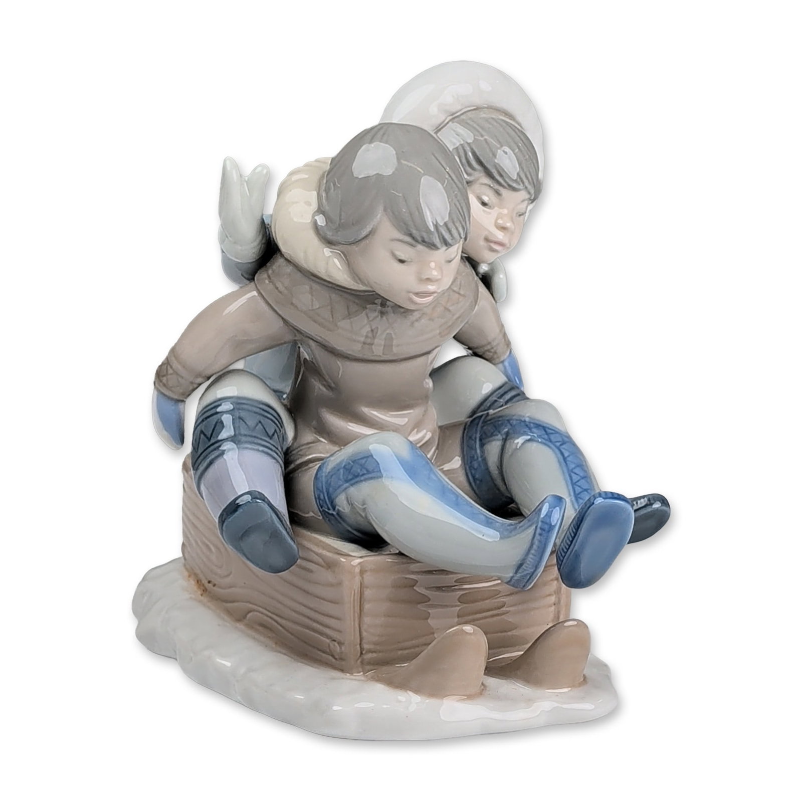 Lladro Porcelain Figurine, Hang On 01005665: Lladro glazed porcelain figurine designed by Francisco Catala. Figurine in glazed porcelain depicting two children in winter parkas and boots huddled together on a wooden-textured sled. Executed in a 