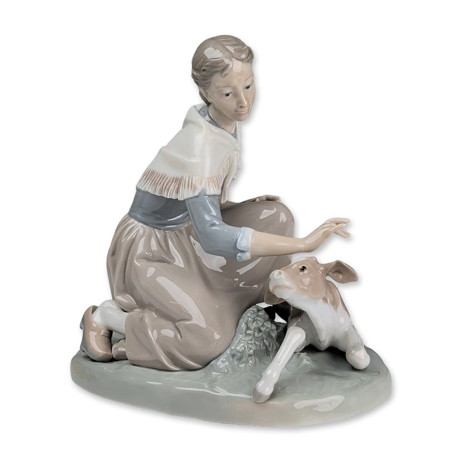 Lladro Porcelain Figurine, Caressing a Little Calf 01004827: Lladro glazed porcelain figurine designed by Salvador Furio. The composition depicts a young woman in a blue blouse and white fringed shawl kneeling to pet a small brown and white calf, with a wooden-