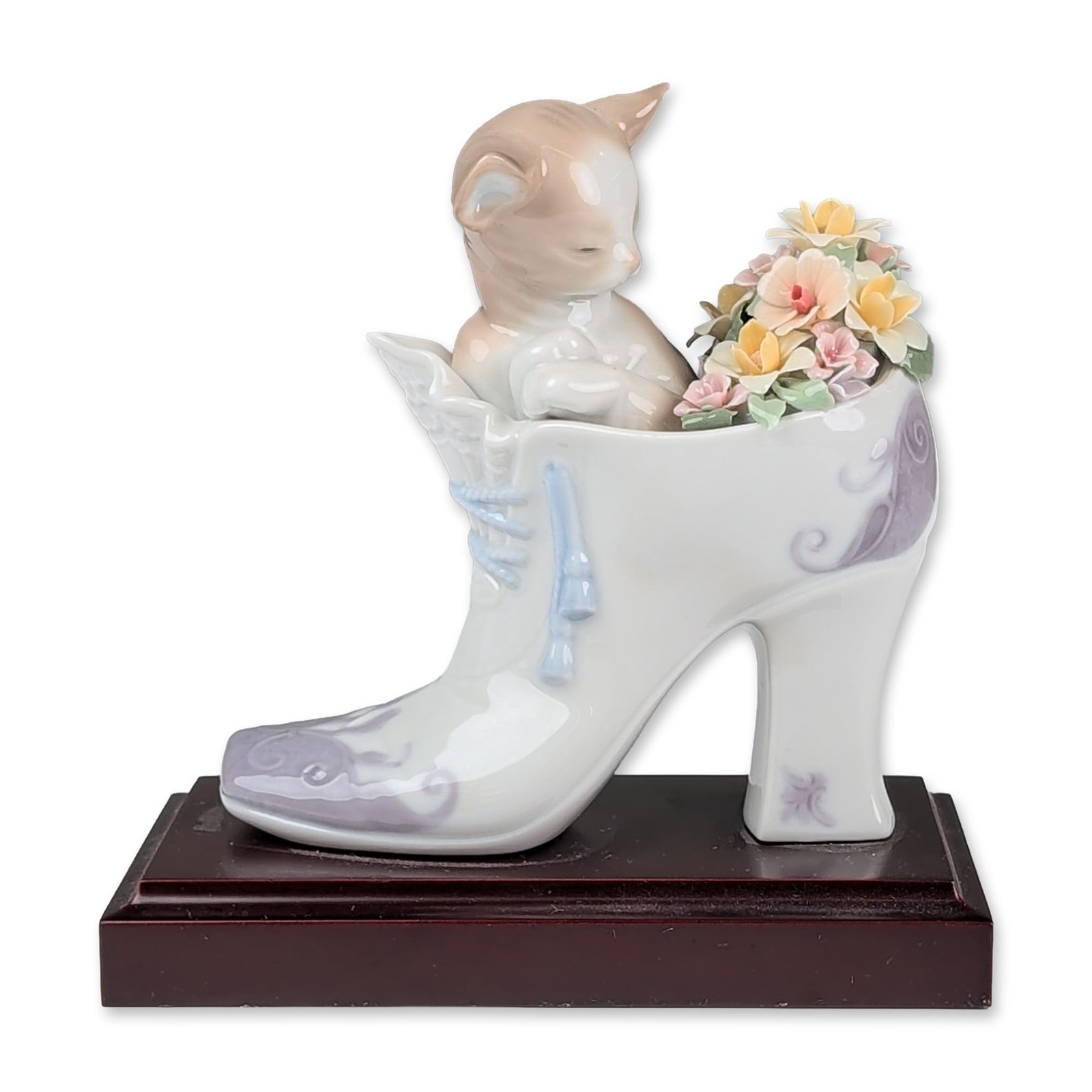 Lladro Porcelain Figurine, A Cozy Fit 01006743: Lladro glazed porcelain figurine depicting a tan and white kitten nestled inside a white high-heeled shoe. The shoe features lavender scrollwork, light blue molded laces, and a ruffled collar. A group