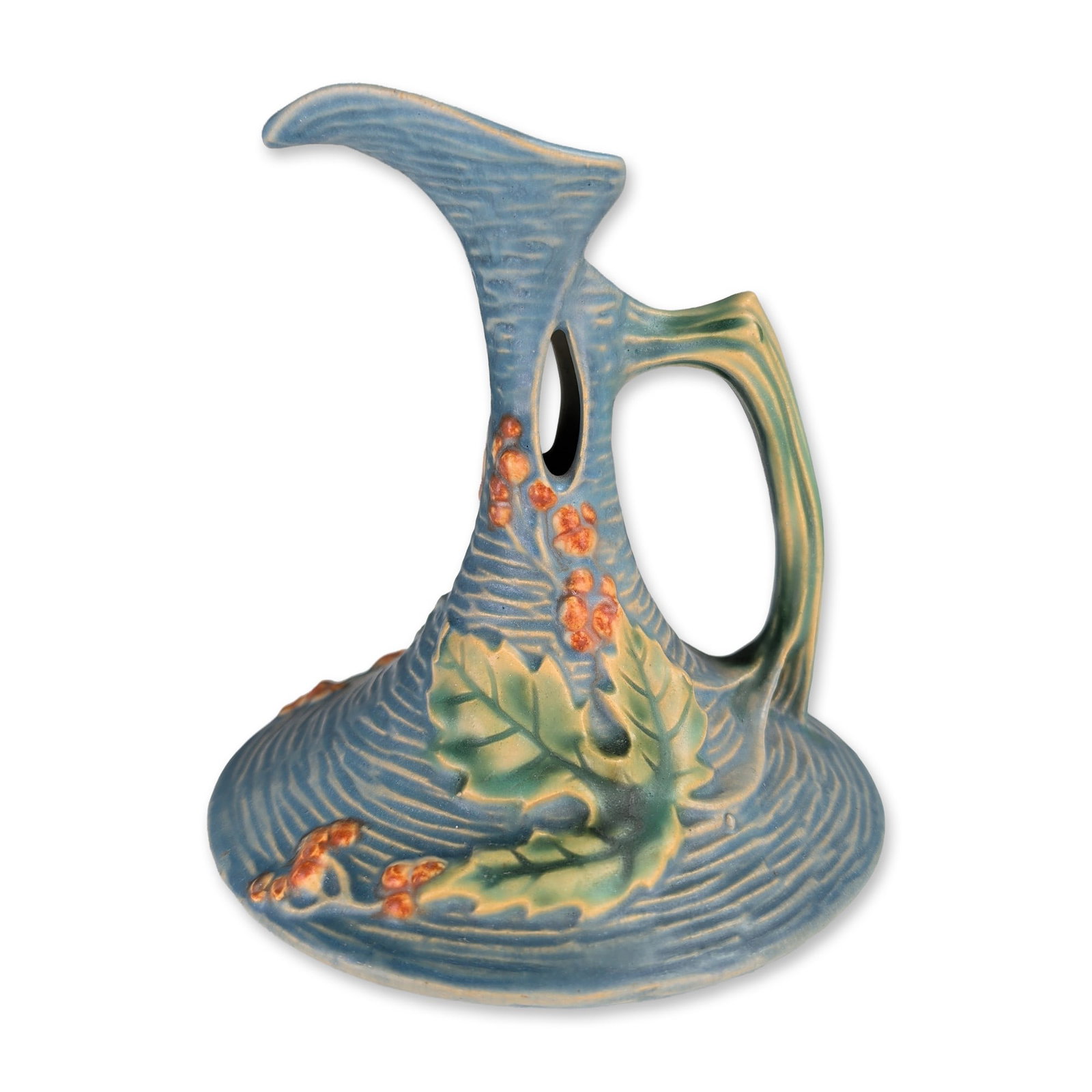 Roseville Art Bushberry Blue Pottery Ewer: Roseville Pottery Company art pottery ewer in the Bushberry pattern, introduced in 1941. The earthenware vessel features a textured blue matte glaze with relief-molded green leaves and orange berries.