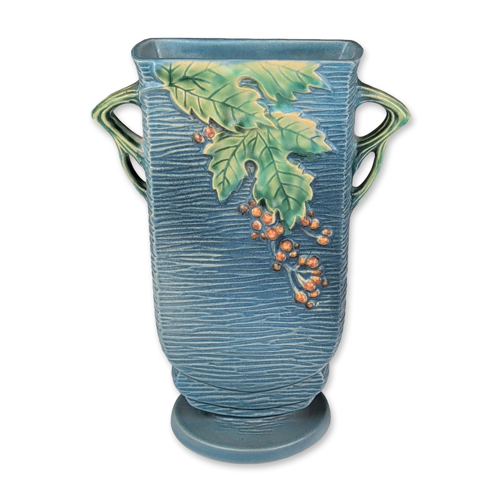Roseville Pottery Dual Handled Vase, Blue Bushberry: Roseville Pottery Company (Zanesville, Ohio) earthenware art pottery vase in the Bushberry pattern, circa 1951. The vessel features a rectangular form with a flared rim and organic branch-style handle