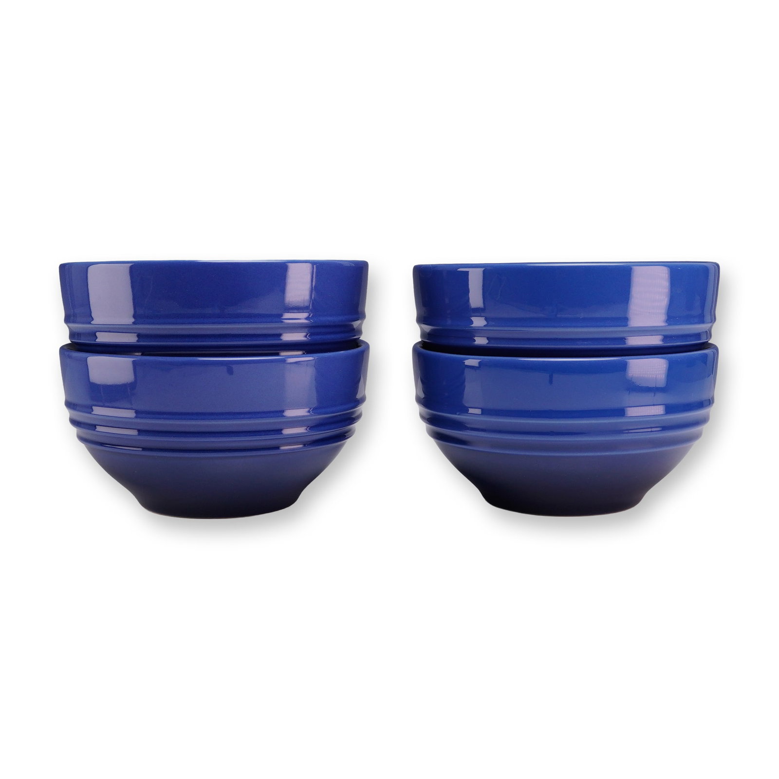 Set of 4 Le Creuset Cobalt Blue Stoneware Cereal Bowls: A set of four glazed stoneware cereal bowls manufactured by Le Creuset. Each bowl is finished in a vibrant cobalt blue glaze and features the brand's signature design of three concentric raised rings 