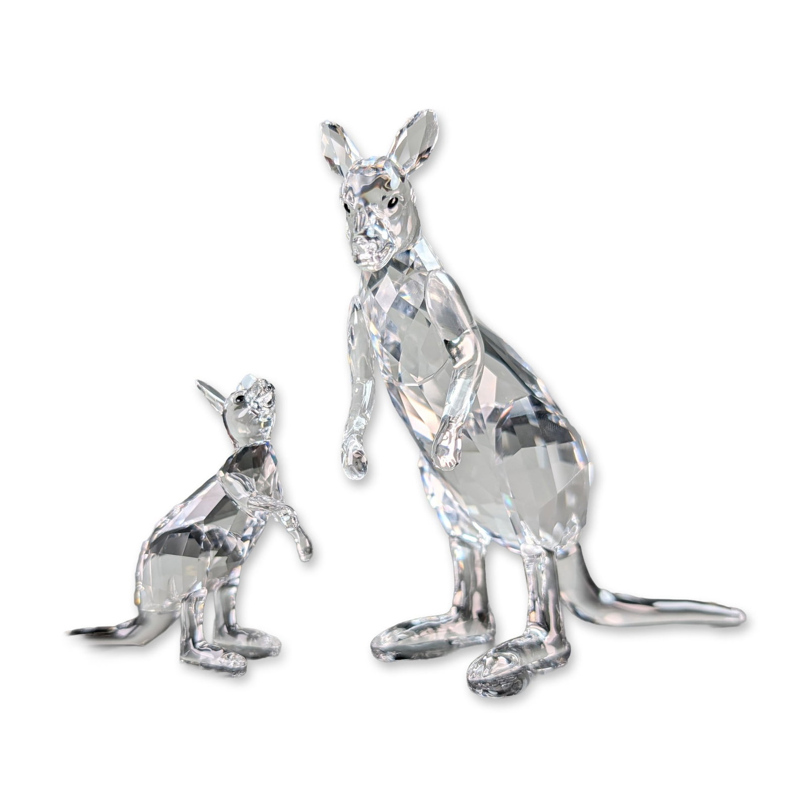 Swarovski Crystal Kangaroo Mother and Baby: Swarovski pair of faceted clear lead crystal figurines depicting a mother kangaroo and her joey. The adult kangaroo is depicted in an upright standing posture using its tail as a tripod support, with 
