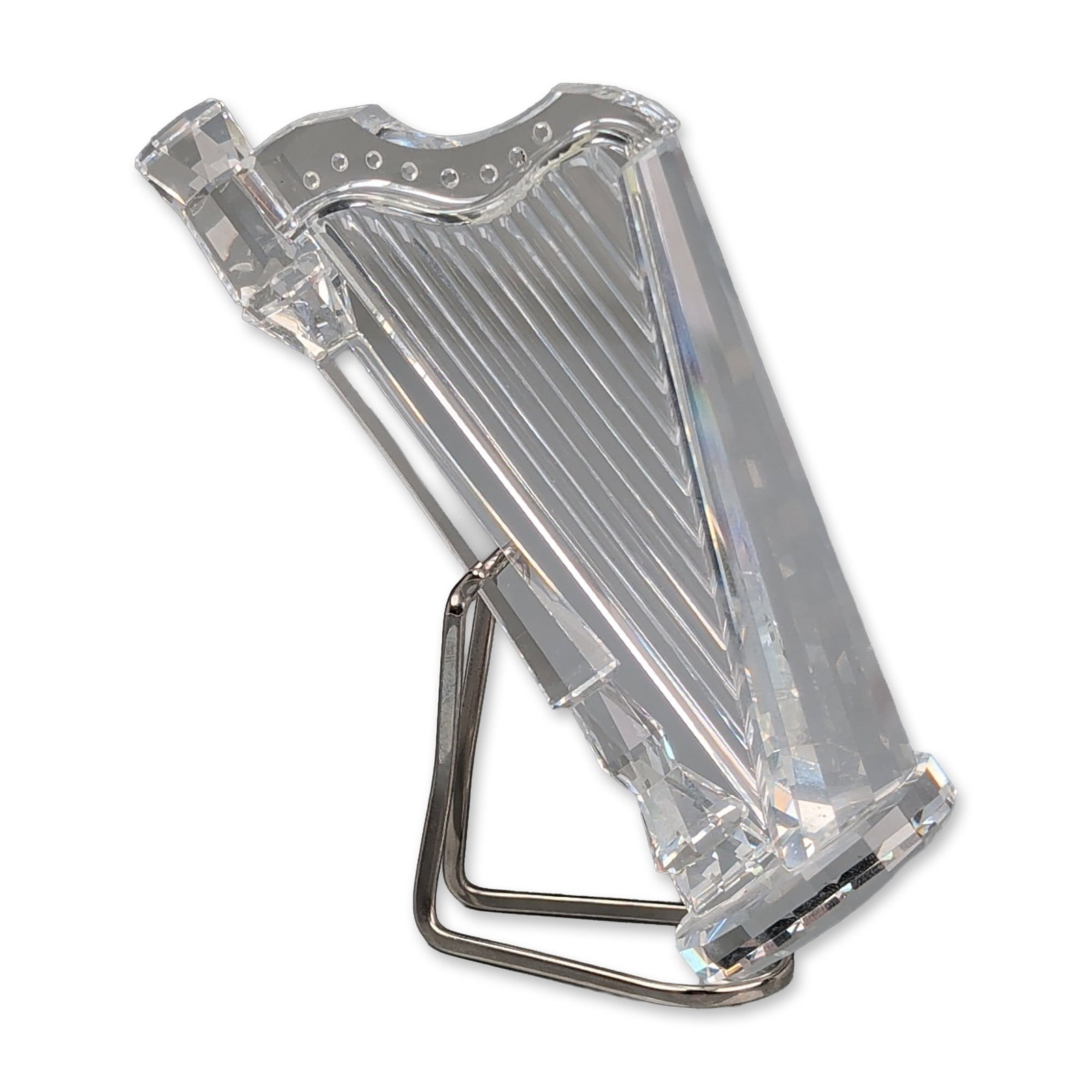 Swarovski Silver Crystal Harp Figurine: Swarovski faceted lead crystal harp figurine from the Crystal Melodies series. The clear crystal form features vertical grooved detailing representing strings and is accompanied by a silver-toned