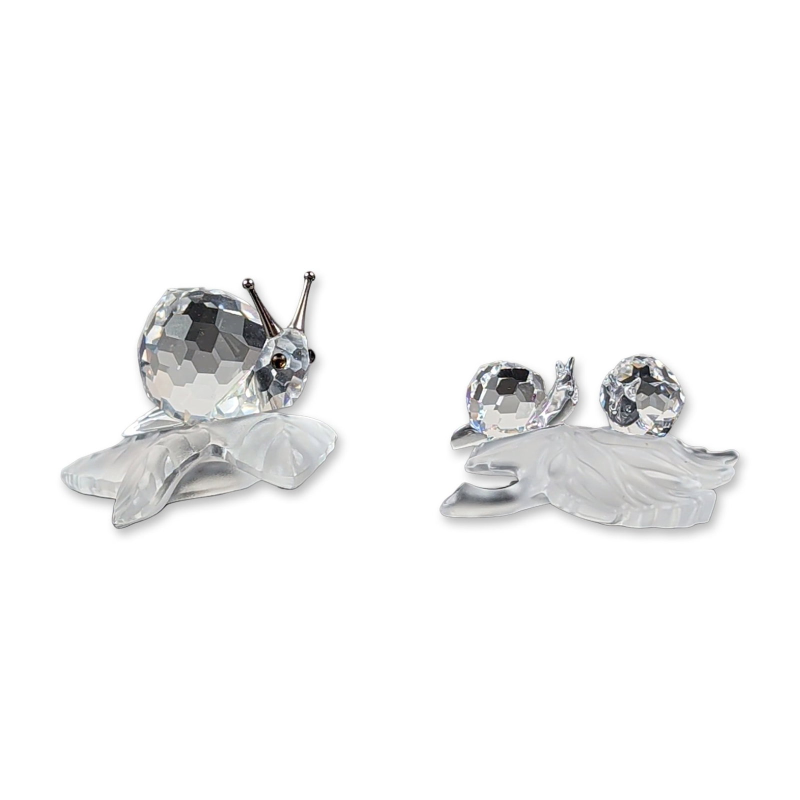 2pc Swarovski Silver Crystal Faceted Crystal Snail Figurines: Swarovski Silver Crystal figurines in faceted lead crystal and frosted glass, depicting snails on leaves. One figurine features a single snail with polychrome eyes and silver-tone metal antennae, the