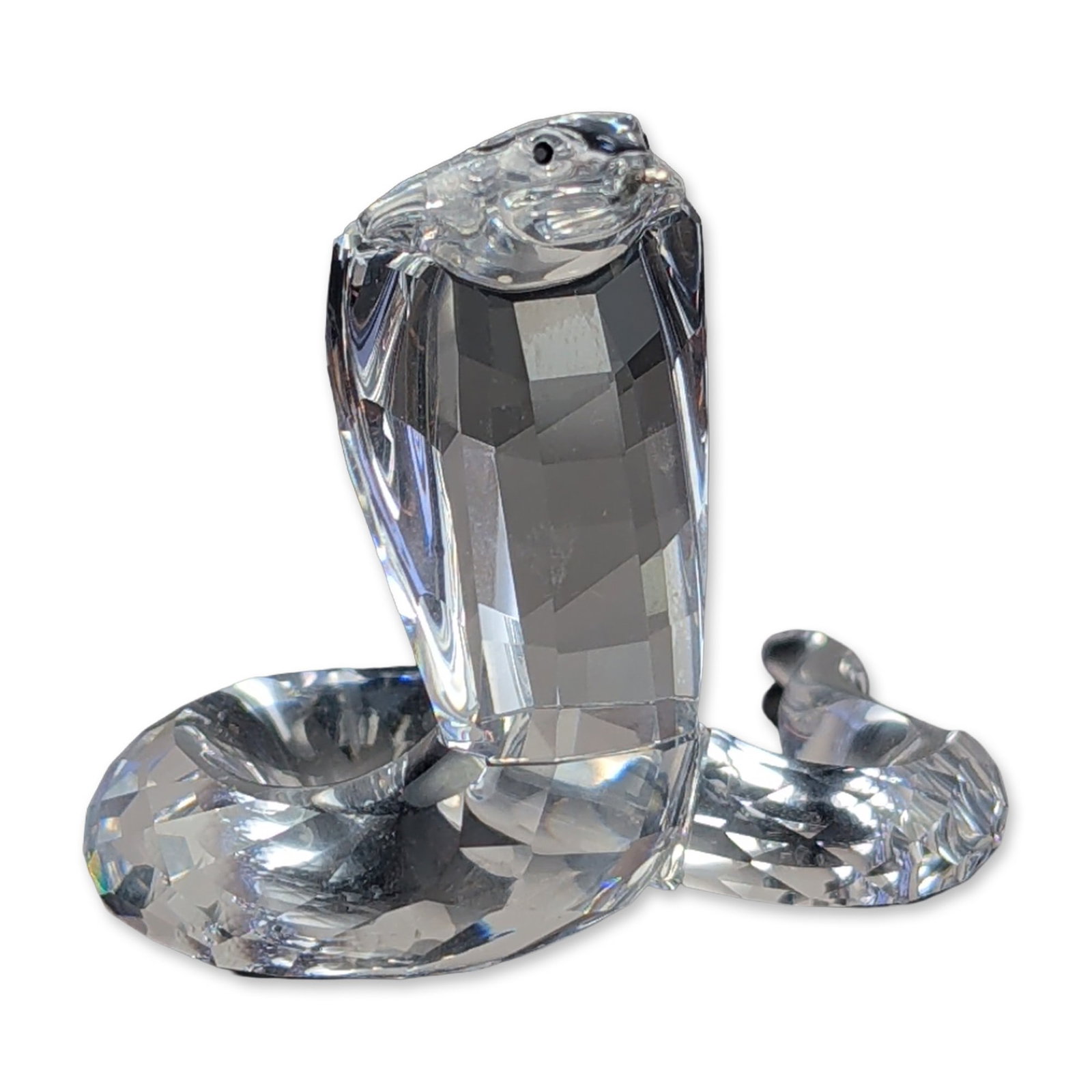 Swarovski Silver Crystal Cobra Figurine: Swarovski Silver Crystal cobra figurine in faceted clear lead crystal. The piece features a coiled form with a prominent faceted head. On the underside of the body is an acid-etched mark featuring a