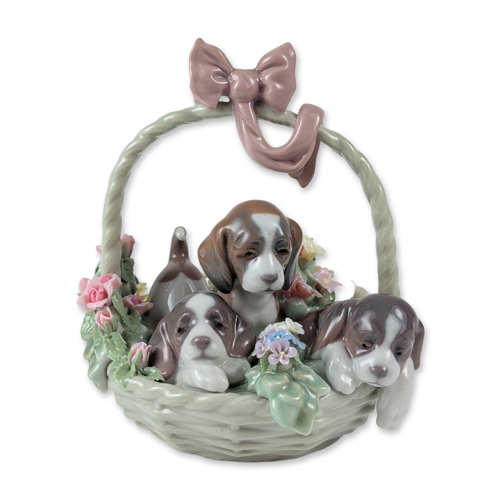 Lladro Porcelain A Litter of Love Figurine 1001441: Lladro glazed porcelain figurine, model 1001441, titled A Litter of Love. The piece depicts three puppies seated within a woven-texture basket featuring a tall handle adorned with a large mauve bow. T