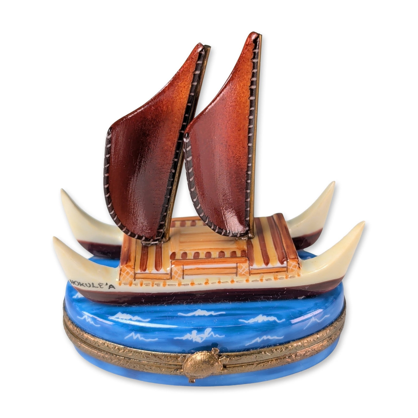 Limoges Hand Painted Hokulea Voyaging Canoe Trinket Box: Limoges porcelain hinged trinket box, hand painted in the form of the Hawaiian voyaging canoe Hokulea. The piece features a double-hulled vessel with cream-toned hulls, a tan deckhouse, and two dark r