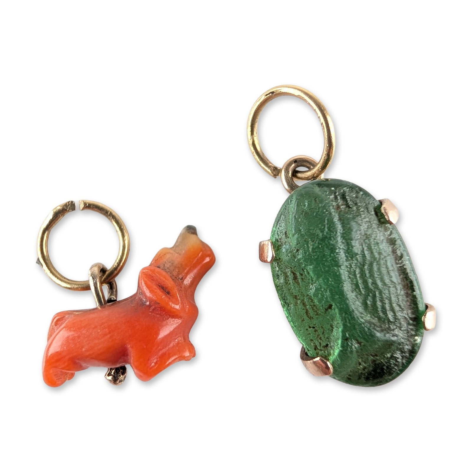Two 14K Yellow Gold, Coral and Glass Animal Pendants: A group of two 14k yellow gold jewelry items. The first is a charm featuring a carved orange-red coral dachshund figure with natural color variations, mounted with a gold pin through the body. The sec