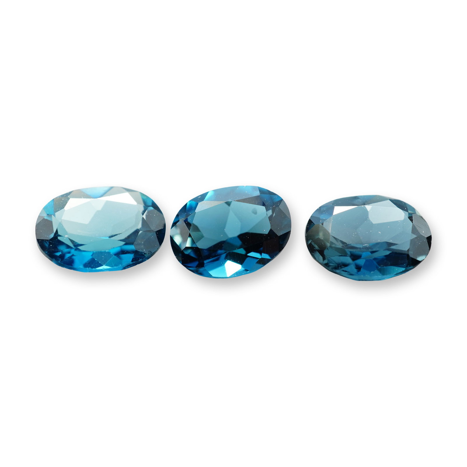 3pc Oval London Blue Topaz Gemstones: Grouping of 3 London Blue Topaz stones. London blue topaz is a highly sought-after gemstone known for its deep, inky blue hue with subtle greenish or grayish undertones. Its calming blue color reduces