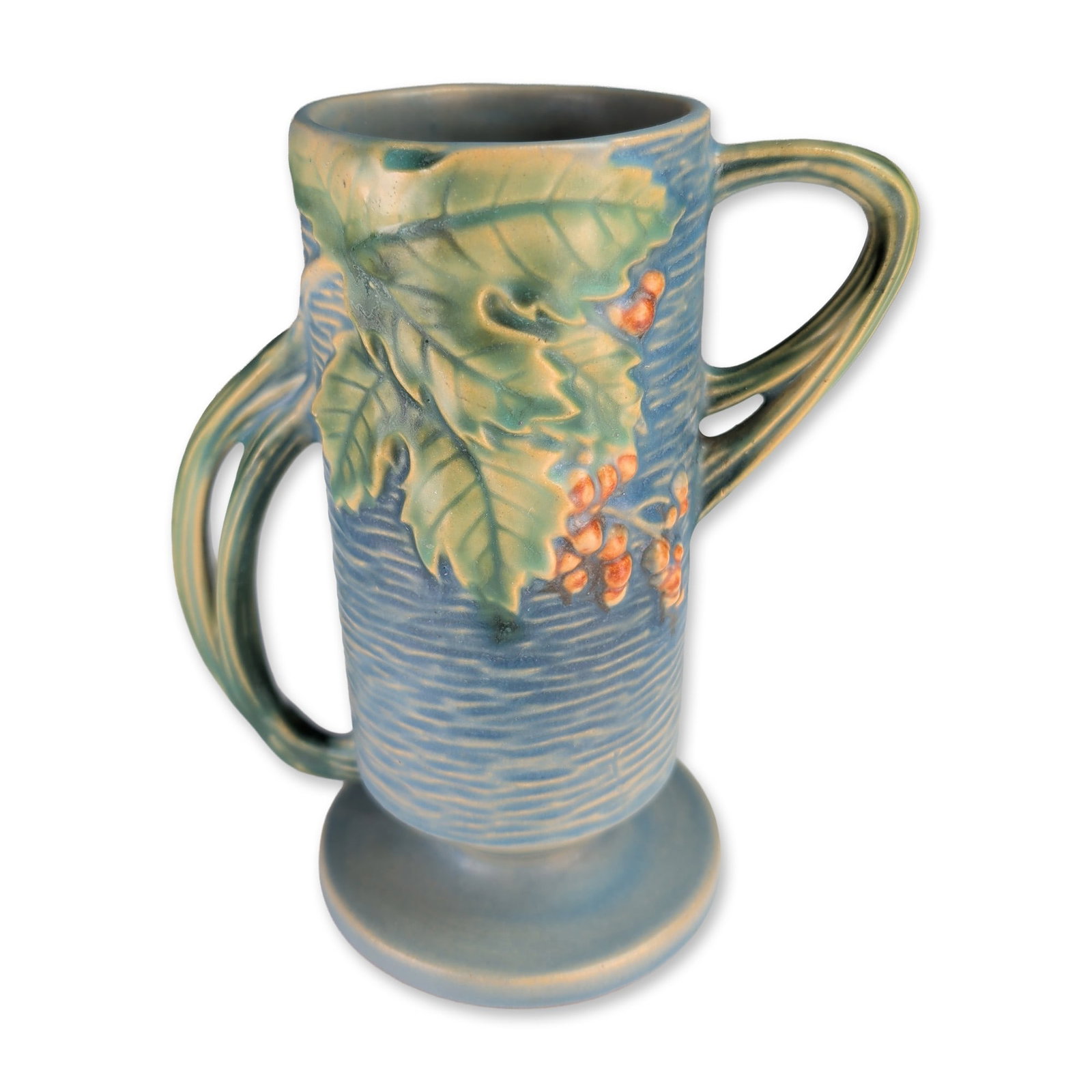 Roseville Bushberry Blue Pottery Vase: Roseville Pottery matte-glazed earthenware double-handled vase in the Bushberry pattern, featuring a cylindrical form with a bark-textured blue ground, relief-molded green foliage, and orange berries.
