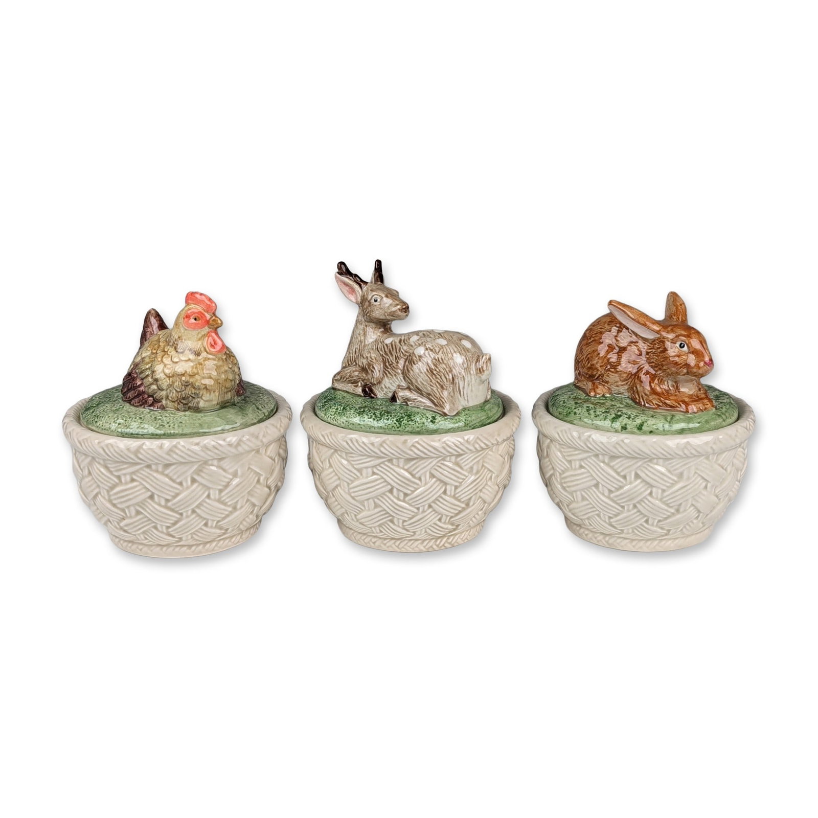 Three Fitz and Floyd Ironstone Lidded Animal Finial Jars: Fitz and Floyd, Japan. Set of three ironstone lidded jars with molded basketweave bases in an off-white glaze. The lids are designed as green mounds, each featuring a hand-glazed animal finial includi