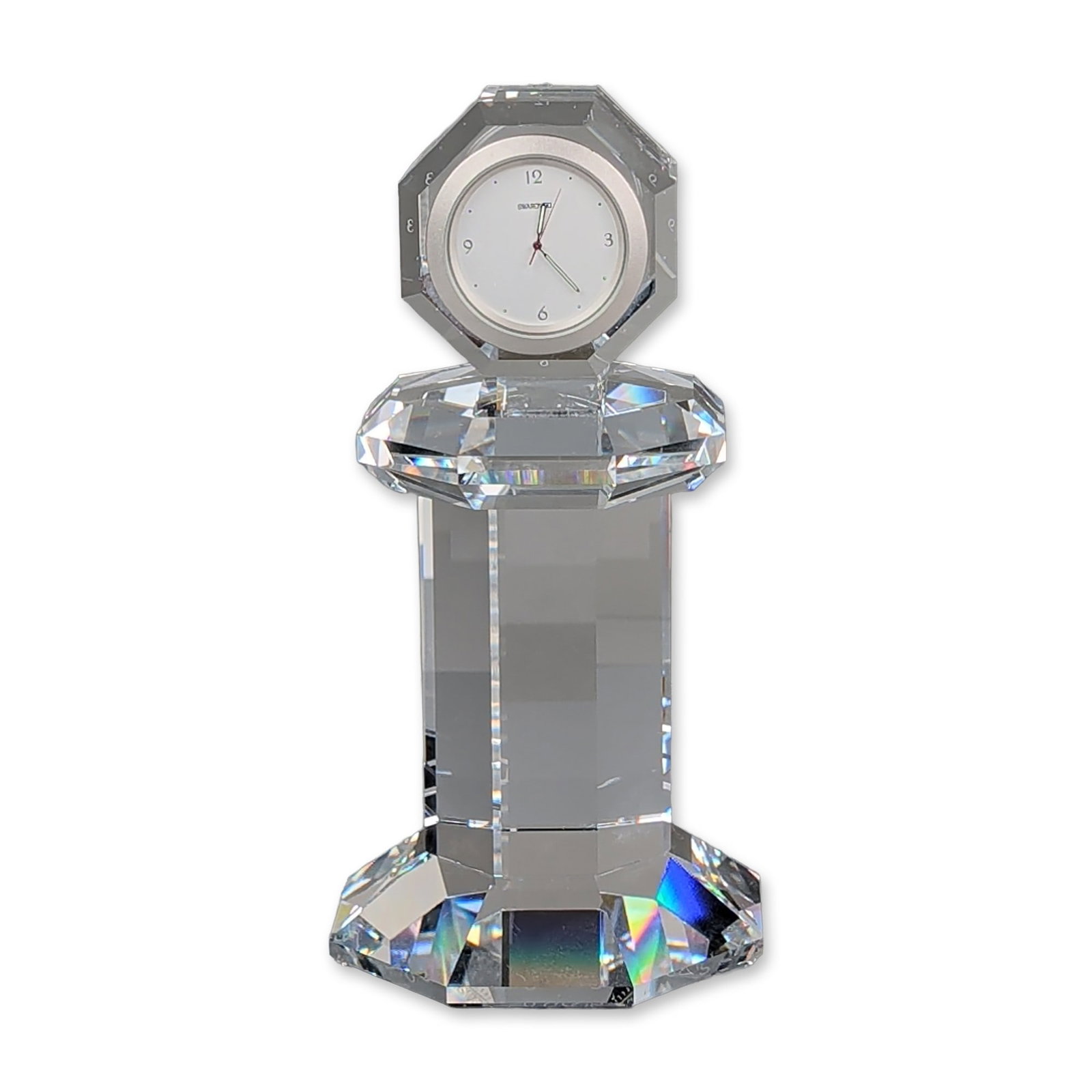 Swarovski Crystal Providence Table Clock, Signed: Swarovski Selection desk clock in faceted lead crystal, designed by Steven Weinberg. The clock features a multifaceted geometric body and an octagonal base. The circular white dial is set within a sil