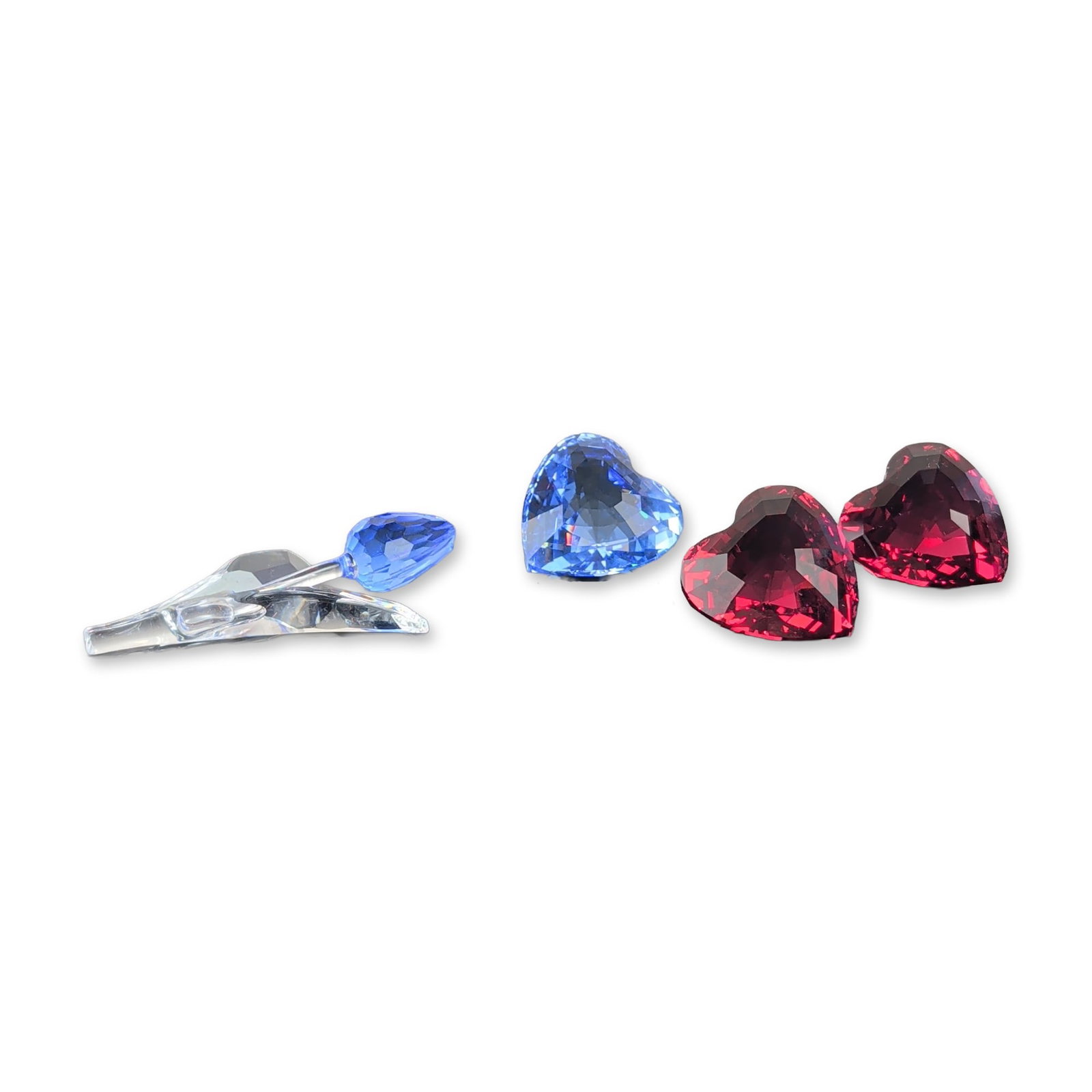 4pc Swarovski Crystal Hearts and Tulip Collection: Swarovski. A group of faceted crystal items in ruby red, sapphire blue, and clear colors, featuring heart-shaped decorative stones faceted on both sides and a tulip figurine with a blue bud and smooth