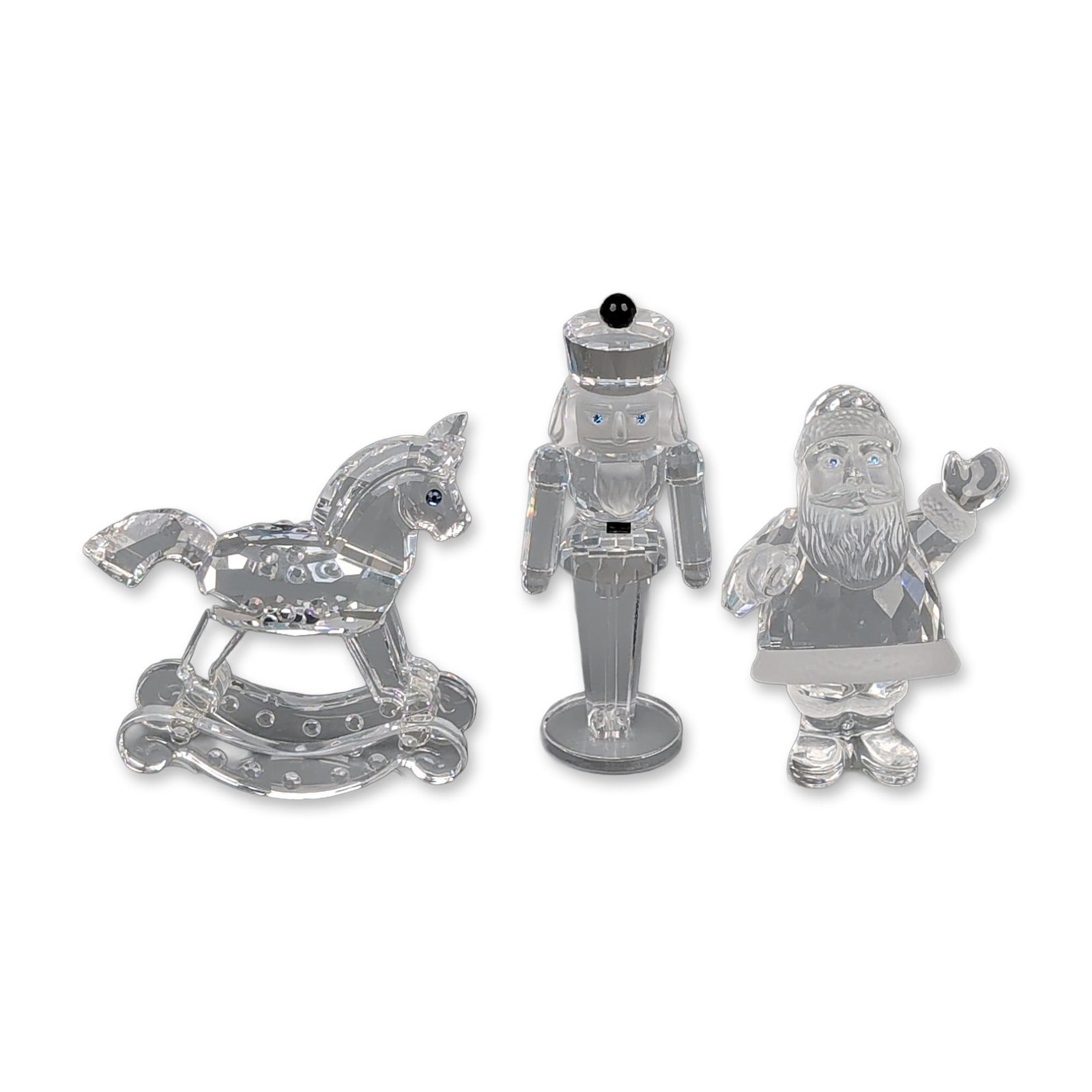 Three Swarovski Silver Crystal Figurines, Rocking Horse, Santa & Nutcracker: Swarovski Silver Crystal holiday figurine trio in faceted and frosted lead crystal, including a rocking horse, a nutcracker, and a Santa Claus. The rocking horse features faceted construction with dar