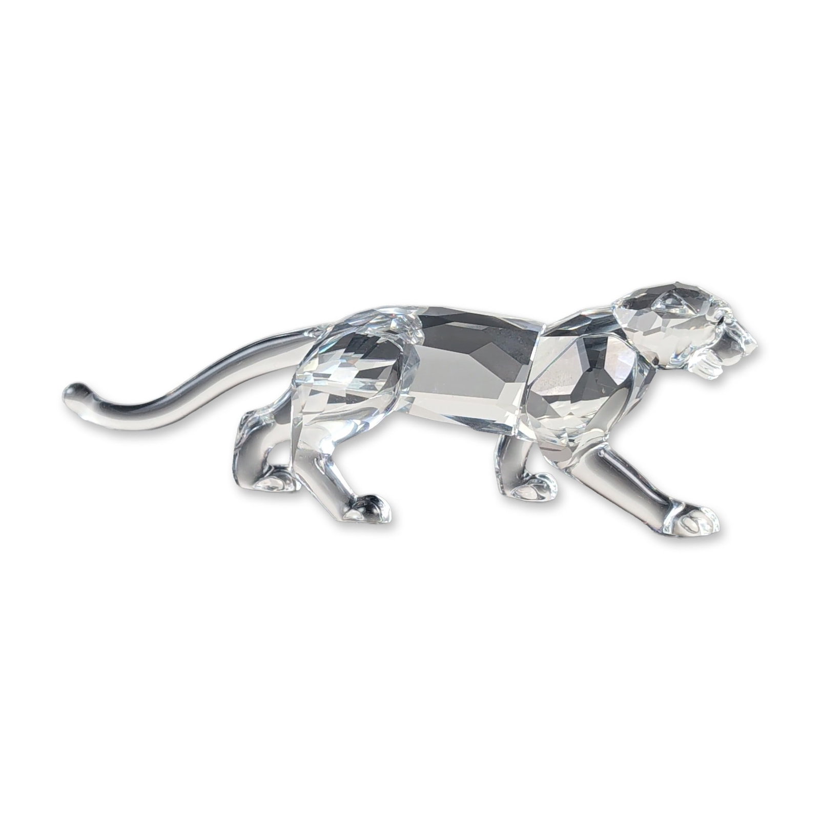 Swarovski Crystal Stalking Leopard Figurine: African Wildlife leopard figurine in faceted lead crystal, modeled in a dynamic low-profile pose with a long-curved tail and inset Moroda eyes. The underside of one hind paw bears an acid-etched mark 