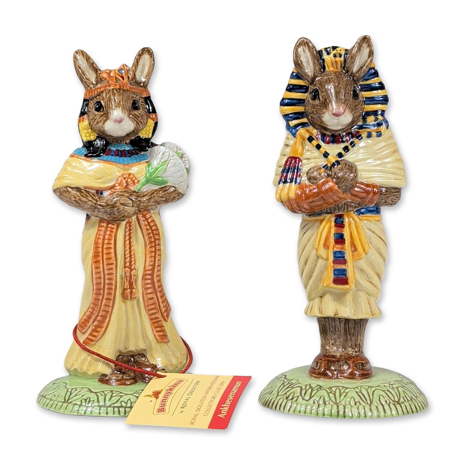 2pc Royal Doulton Bunnykins Egyptian Series Figurines: Royal Doulton, United Kingdom. Pair of hand-decorated ceramic Bunnykins figurines from the Egyptian series, featuring Tutankhamun (DB 296) and Ankhesenamun (DB 295). Tutankhamun is depicted in a blue 