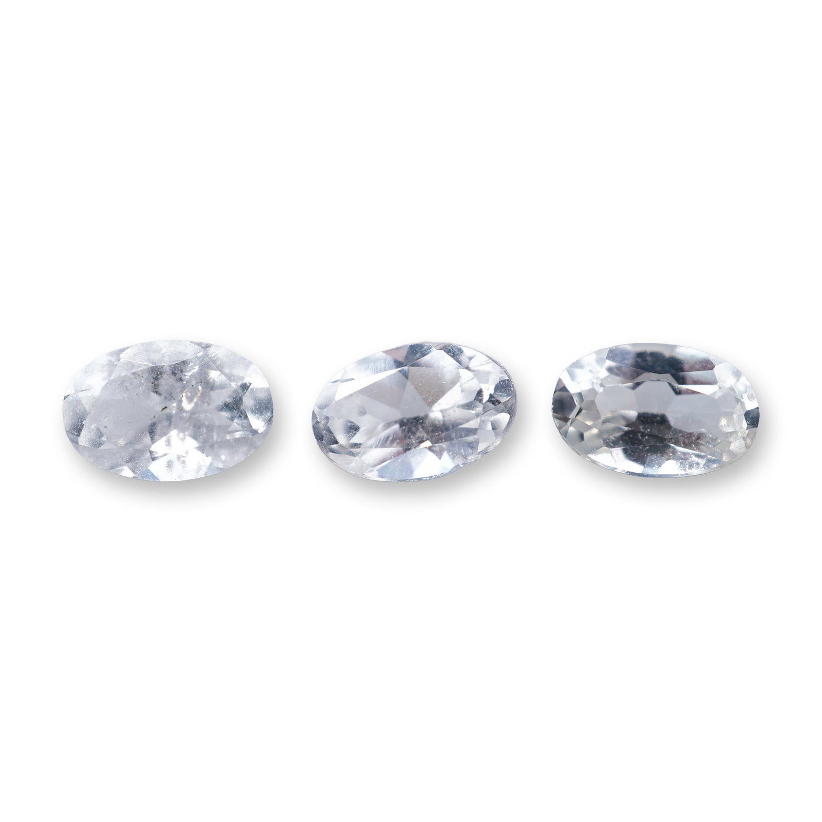 Trio of Oval Cut Aquamarine Gemstones: Trio of loose aquamarine gemstones featuring oval faceted cuts and colorless transparency. The stones exhibit visible internal inclusions including small pinpoints and faint wispy feathers. 1.6ct