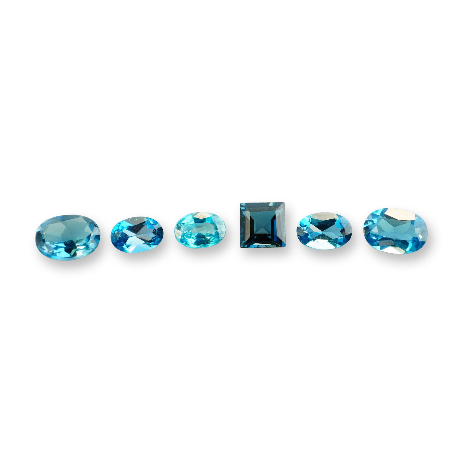 6pc London Blue Topaz Gemstones: Grouping of 6 London Blue Topaz stones. London blue topaz is a highly sought-after gemstone known for its deep, inky blue hue with subtle greenish or grayish undertones. Its calming blue color