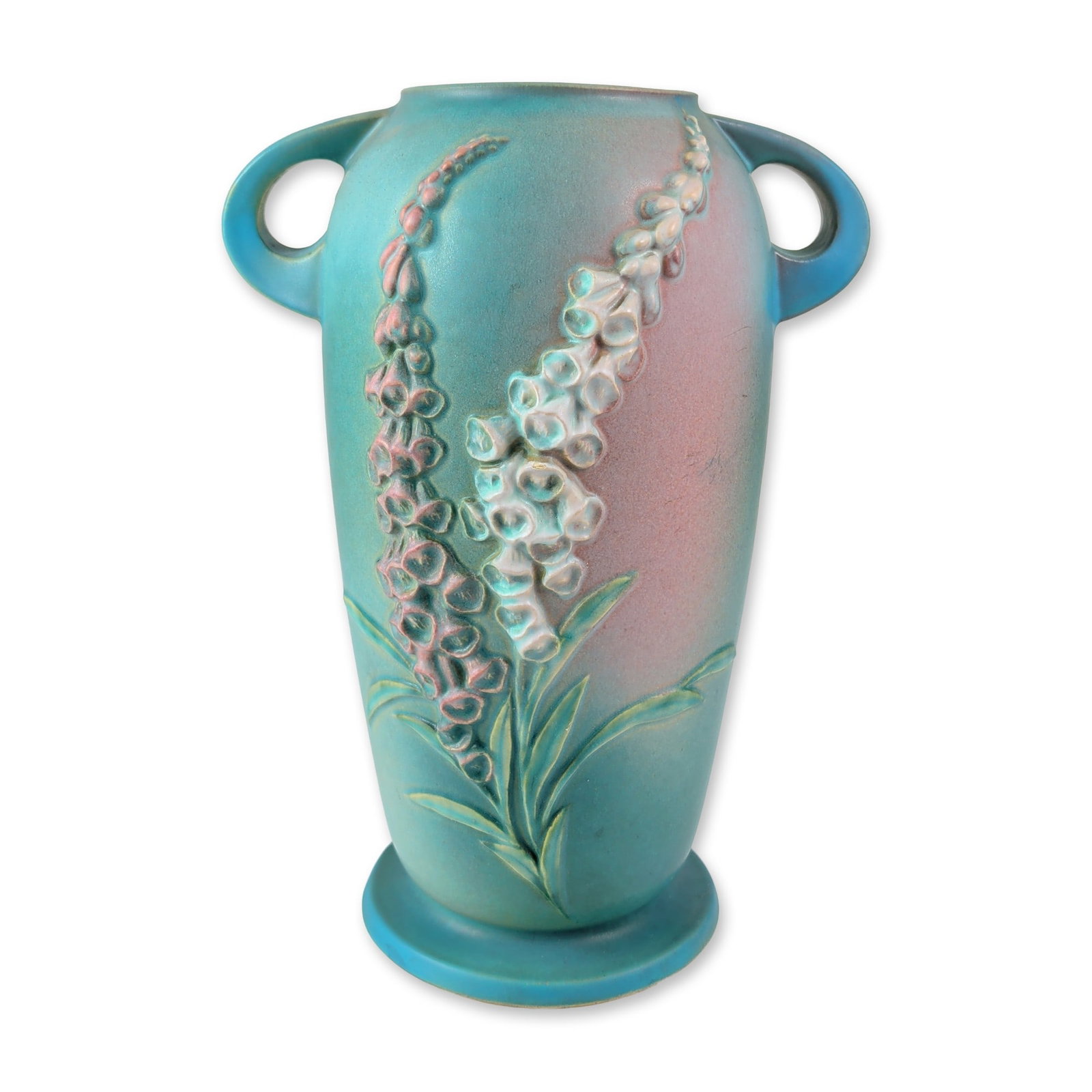 Roseville Foxglove Pattern Ceramic Double-Handled Pedestal Vase: Roseville Pottery Company earthenware pedestal vase in the Foxglove pattern, featuring a matte blue glaze with a pink gradient blush. The body is decorated with relief-molded foxglove floral sprays in