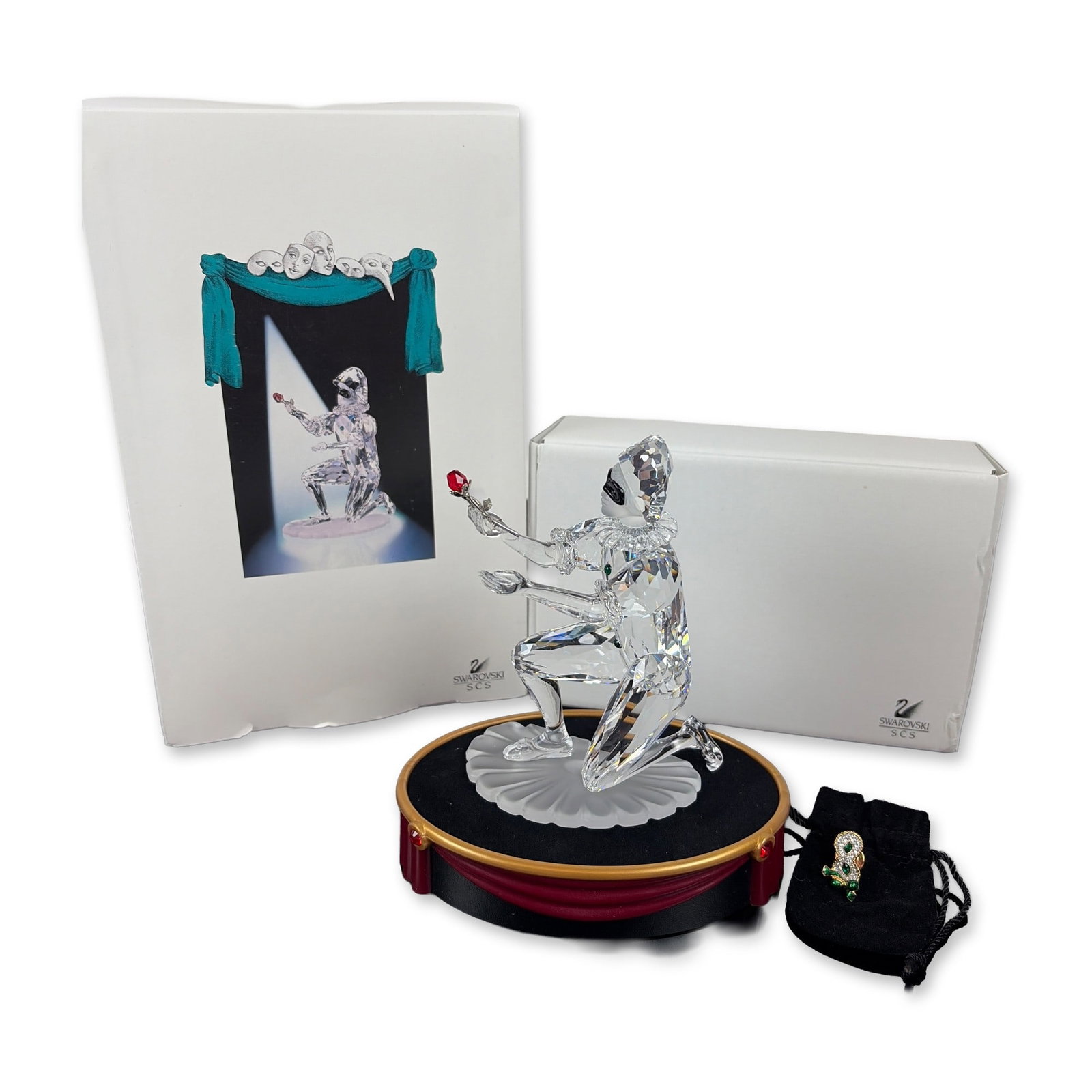3pc Swarovski SCS 2001 Annual Edition Harlequin Crystal Figurine, Pin, and Base: This 3-piece set features a Swarovski figurine, pin, and base. Designed by Anton Hirzinger, it is the second release in the Masquerade trilogy. The clear faceted lead crystal figure is posed dynamical