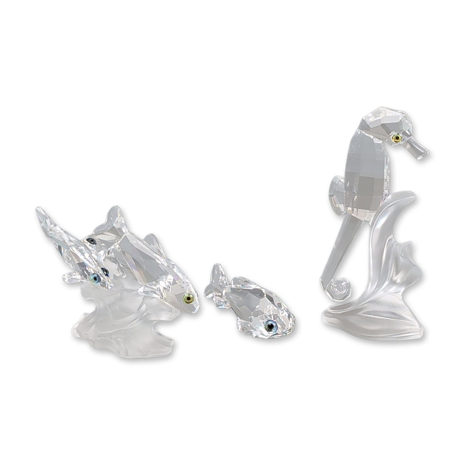 Three Swarovski Crystal South Sea Figurines, Seahorse and Fish: Swarovski Silver Crystal figurines from the South Sea aquatic collection. The lot features a multifaceted clear crystal seahorse with a yellow-toned eye on a frosted crystal base, a school of faceted 