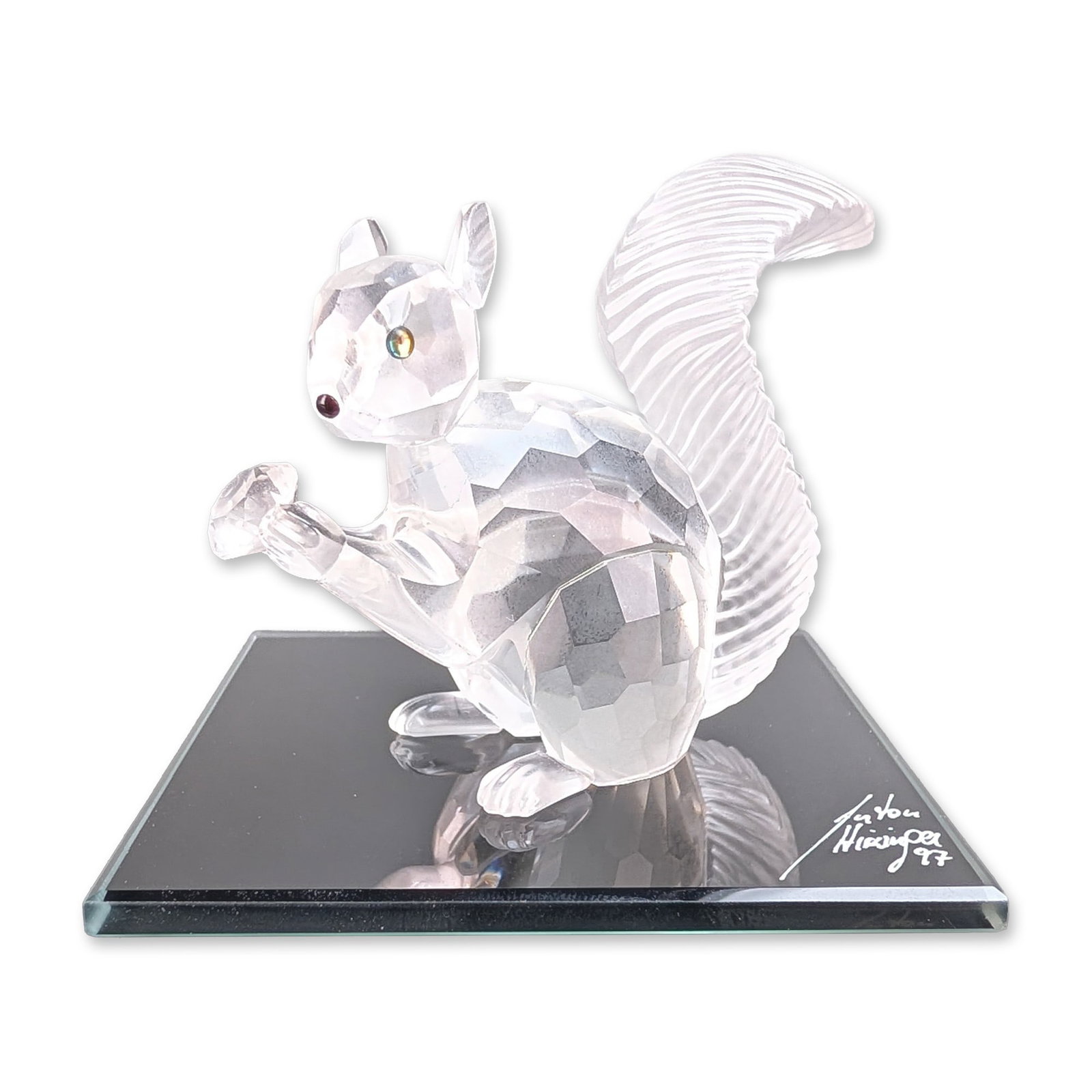 Swarovski SCS 1997 Squirrel Crystal Figurine w/ Mirror Base: Swarovski SCS annual edition 1997. The Squirrel crystal figurine in faceted clear lead crystal, depicting a seated squirrel holding a faceted acorn with dark crystal eyes and a textured frosted tail. 