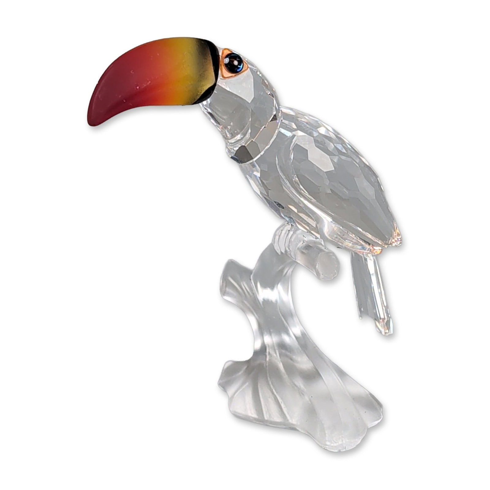 Swarovski Crystal Figurine, Toucan Colored Beak: Swarovski Silver Crystal. Toucan figurine in faceted clear crystal, featuring a multi-color gradient beak transitioning from yellow to red with a black band. The bird is perched on a frosted crystal b