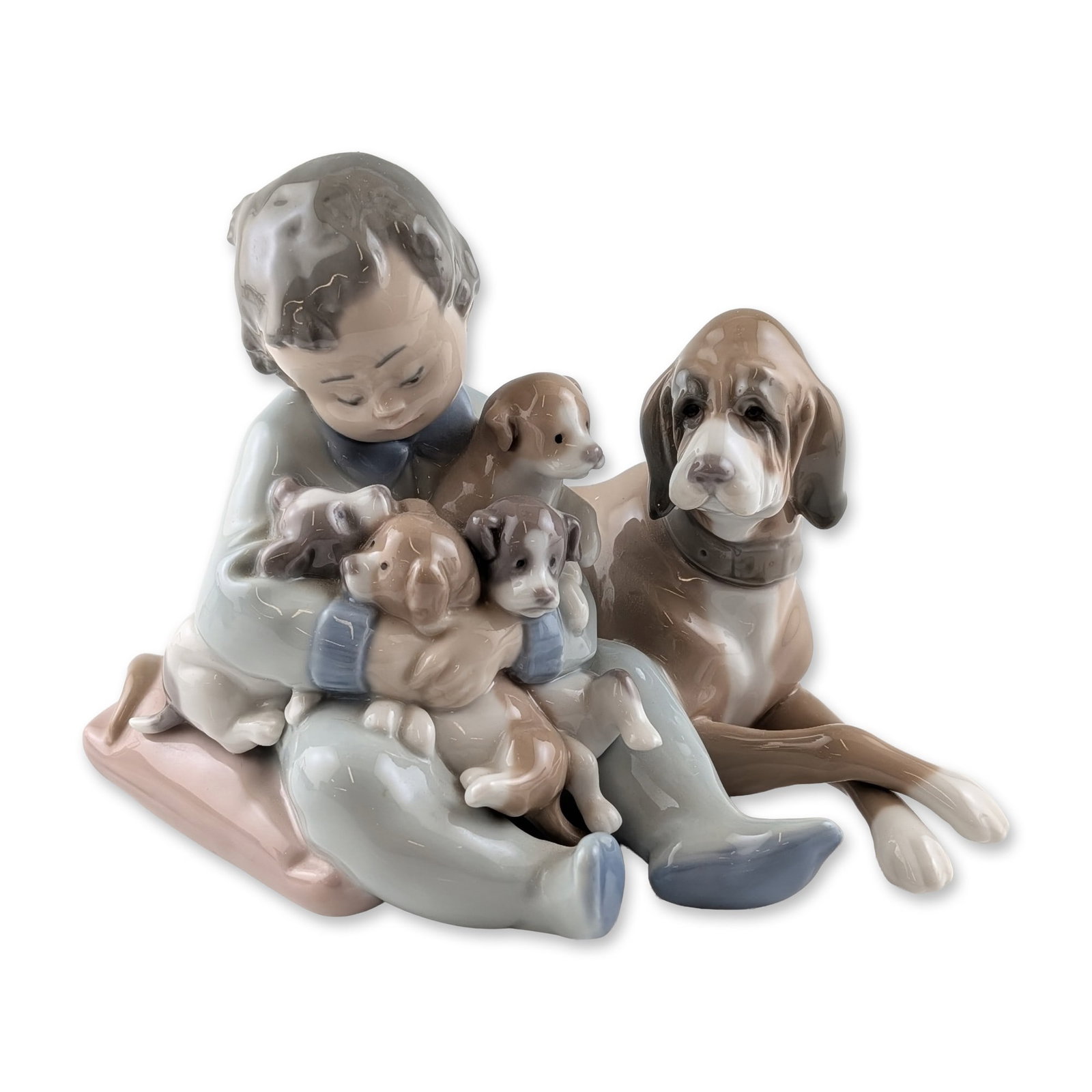 Lladro Spanish Glazed Porcelain New Playmates Figurine: Lladro, Spain. Glazed porcelain figurine titled New Playmates (Mis Amigos), model number 5456, sculpted by Antonio Ramos. The composition features a young boy seated on a large cushion holding four pu