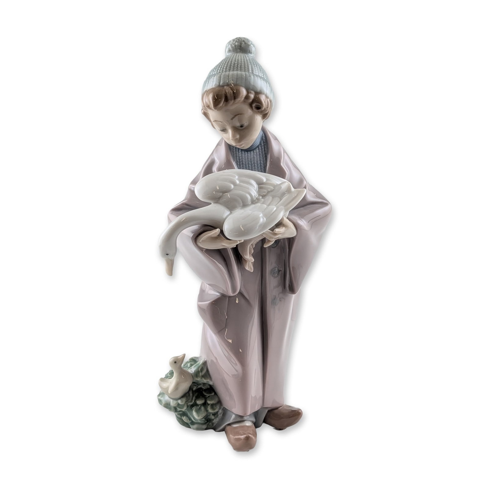 Lladro Follow Us Glazed Porcelain Figurine: Lladro (Spain). Glazed porcelain figurine titled Follow Us, model 6101, by sculptor Salvador Debon. The figure depicts a person in a lavender coat and blue knit beanie holding a large white goose, wit