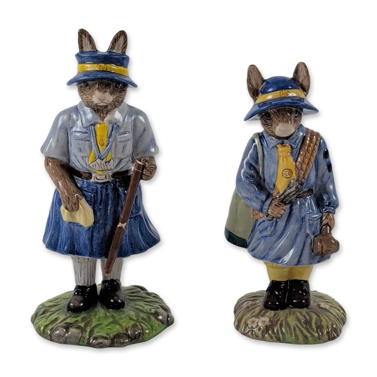 2pc Royal Doulton Bunnykins Ceramic Scouting Figurines: Pair of Royal Doulton Bunnykins glazed ceramic figurines featuring scouting-themed rabbit subjects. Lot includes Model DB 431 Girl Guide depicted in a blue uniform with a yellow neckerchief and green 