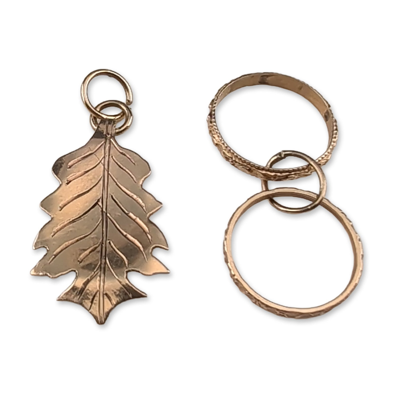 2pc 10K Gold Leaf and Rings Pendant Charms: Contemporary 10k yellow gold jewelry duo. Including two band rings and an oak leaf design. The interior of each ring band bears an impressed mark reading 10K. The leaf is embossed with vein detailing 