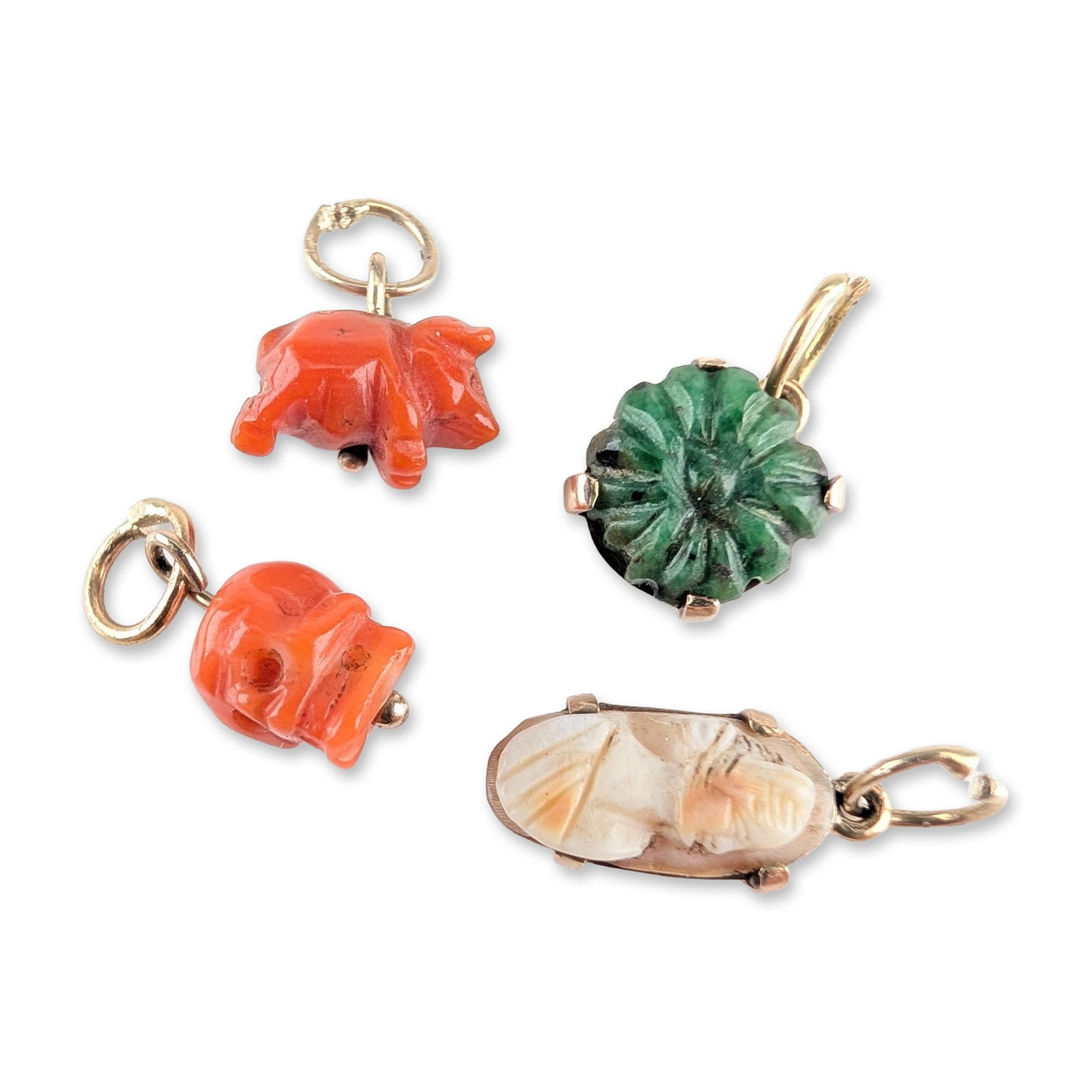 4pc 7K and 10K Gold Vintage Carved Gemstone and Shell Charms: A group of four vintage hand-carved gemstone and shell charms set in yellow gold. The collection includes a red coral skull with hollowed eye sockets and nasal cavity, a red coral pig in a walking pos