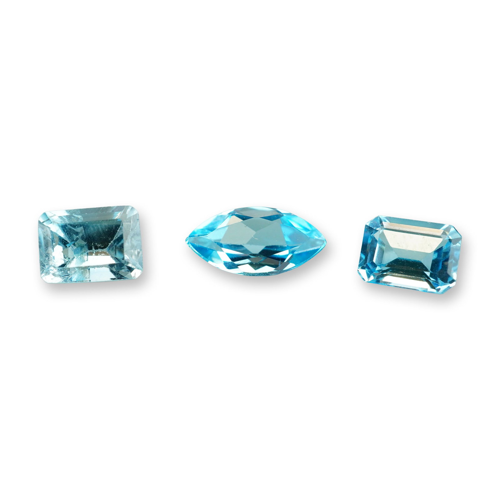 3pc Marquise and Emerald Cut Blue Topaz Gemstones: Grouping of 3 Blue Topaz stones. Emerald cut is 1.5ct and marquise is 1.24ct. Blue topaz is a striking, durable semi-precious gemstone known for its glassy luster and excellent clarity. Blue topaz mea