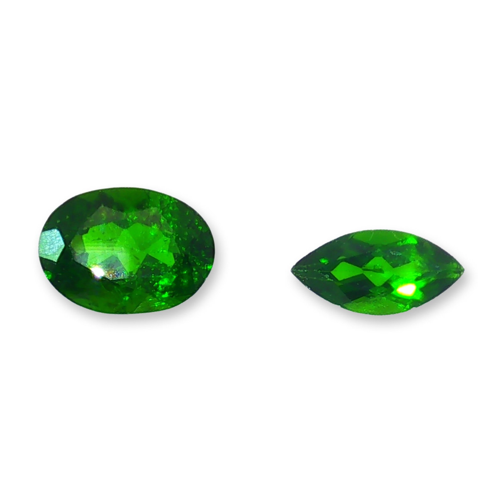 Pair of Loose Green Diopside Gemstones: A pair of loose faceted gemstones that appear to be natural green diopside. The lot features one oval-cut and one marquise-cut stone, showcasing vibrant green hues and the rich, saturated color charac