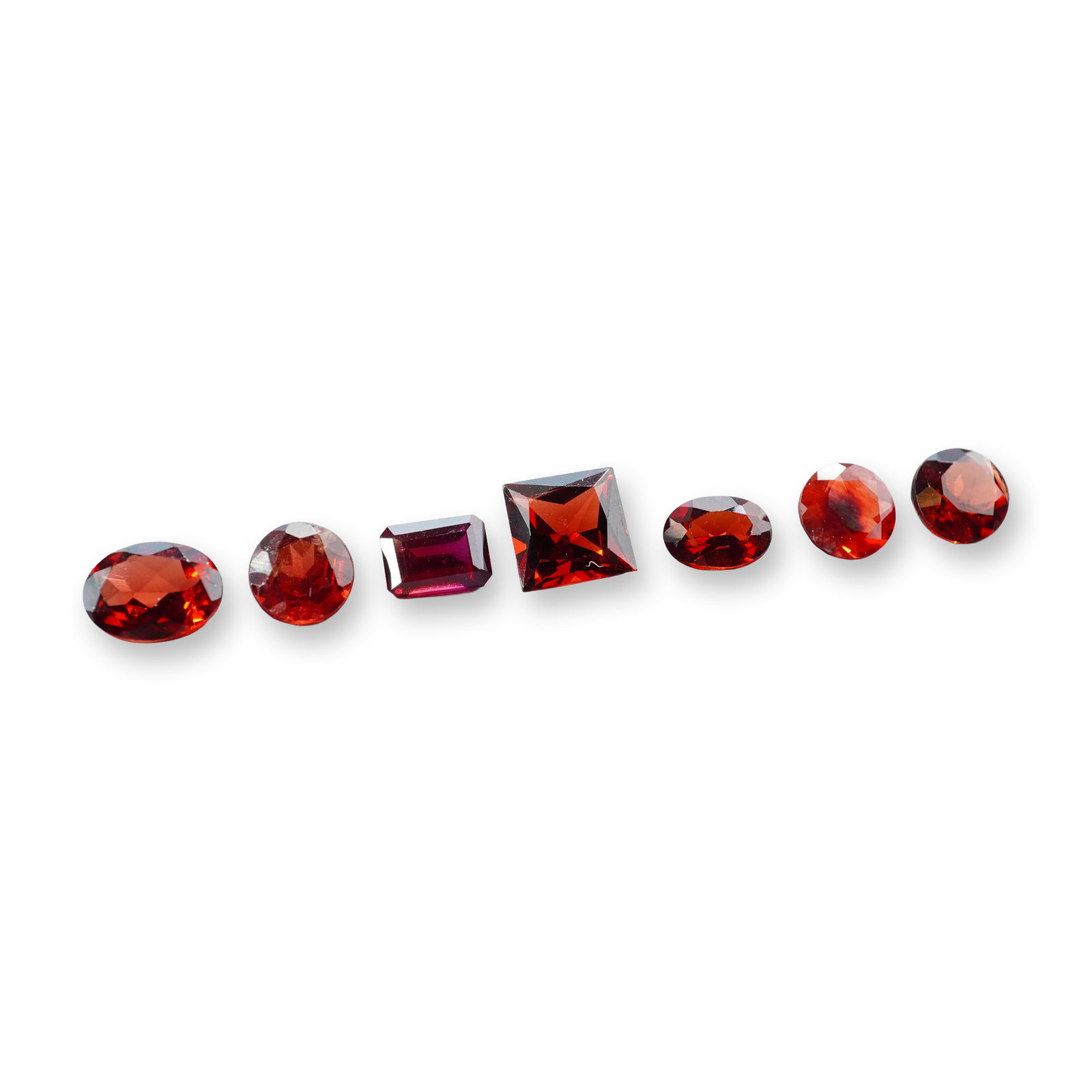 7pc Red Garnet Gemstones in Vatious Shapes and Sizes: Grouping of 7 garnet gemstones. The spiritual meaning of a garnet centers on vitality, protection, and devotion. Known as a stone of passion and commitment, it is highly valued for grounding scattered