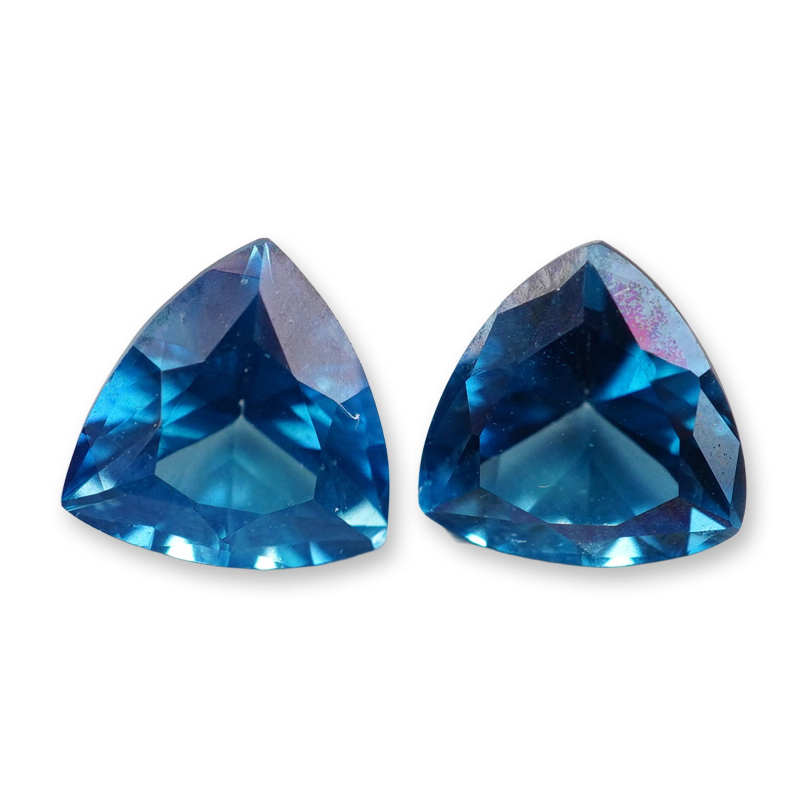 2pc London Blue Topaz Gemstones: Grouping of 2 London Blue Topaz stones. London blue topaz is a highly sought-after gemstone known for its deep, inky blue hue with subtle greenish or grayish undertones. Its calming blue color reduces