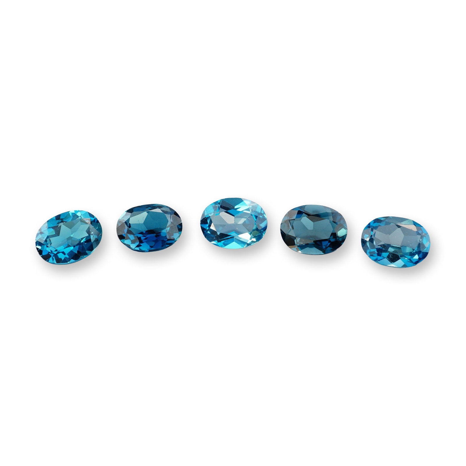 5pc Oval London Blue Topaz Gemstones: Grouping of 5 London Blue Topaz stones. London blue topaz is a highly sought-after gemstone known for its deep, inky blue hue with subtle greenish or grayish undertones. Its calming blue color