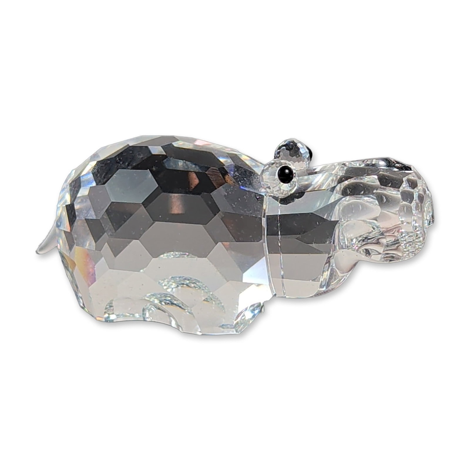 Swarovski Crystal African Wildlife Hippopotamus Figurine: Swarovski. Hippopotamus figurine in faceted clear lead crystal, featuring two black jet crystal eyes and a pointed tail. The underside of the rear body is marked with an etched swan logo. The item inc